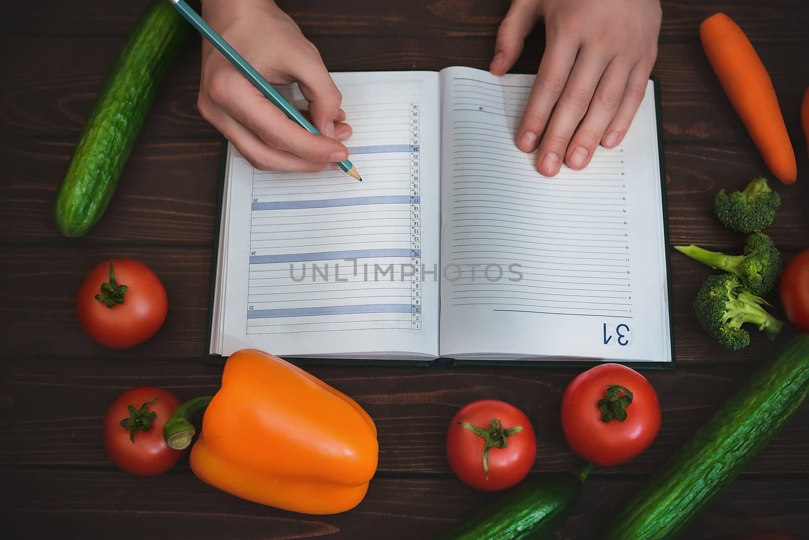 Dieting concept with a notepad and pen surrounded by lots of healthy fresh vegetables.