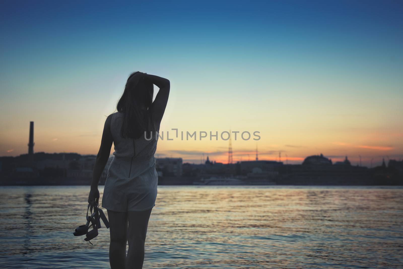 girl standing on the beach, watching the sunset