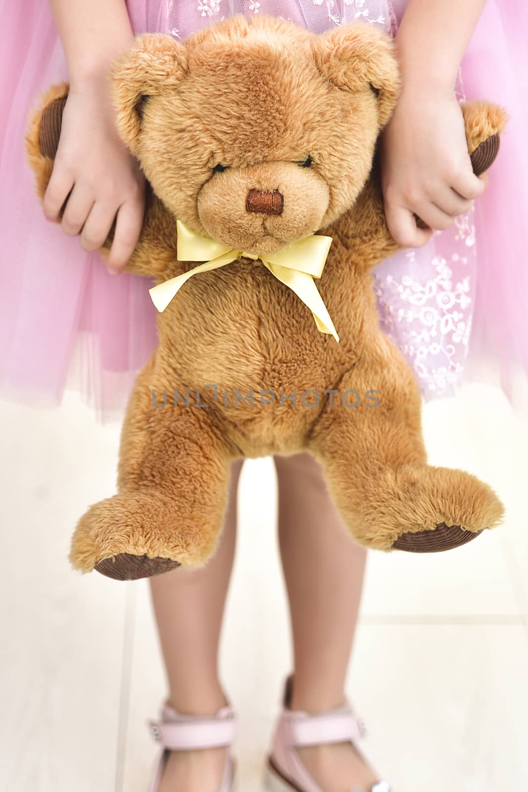 Child in wedding dress with bear. Close up White background