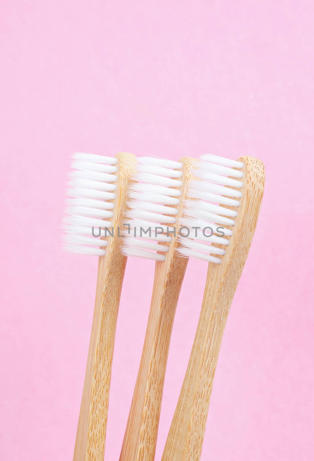 Bamboo toothbrushes on pink background. by Gamjai