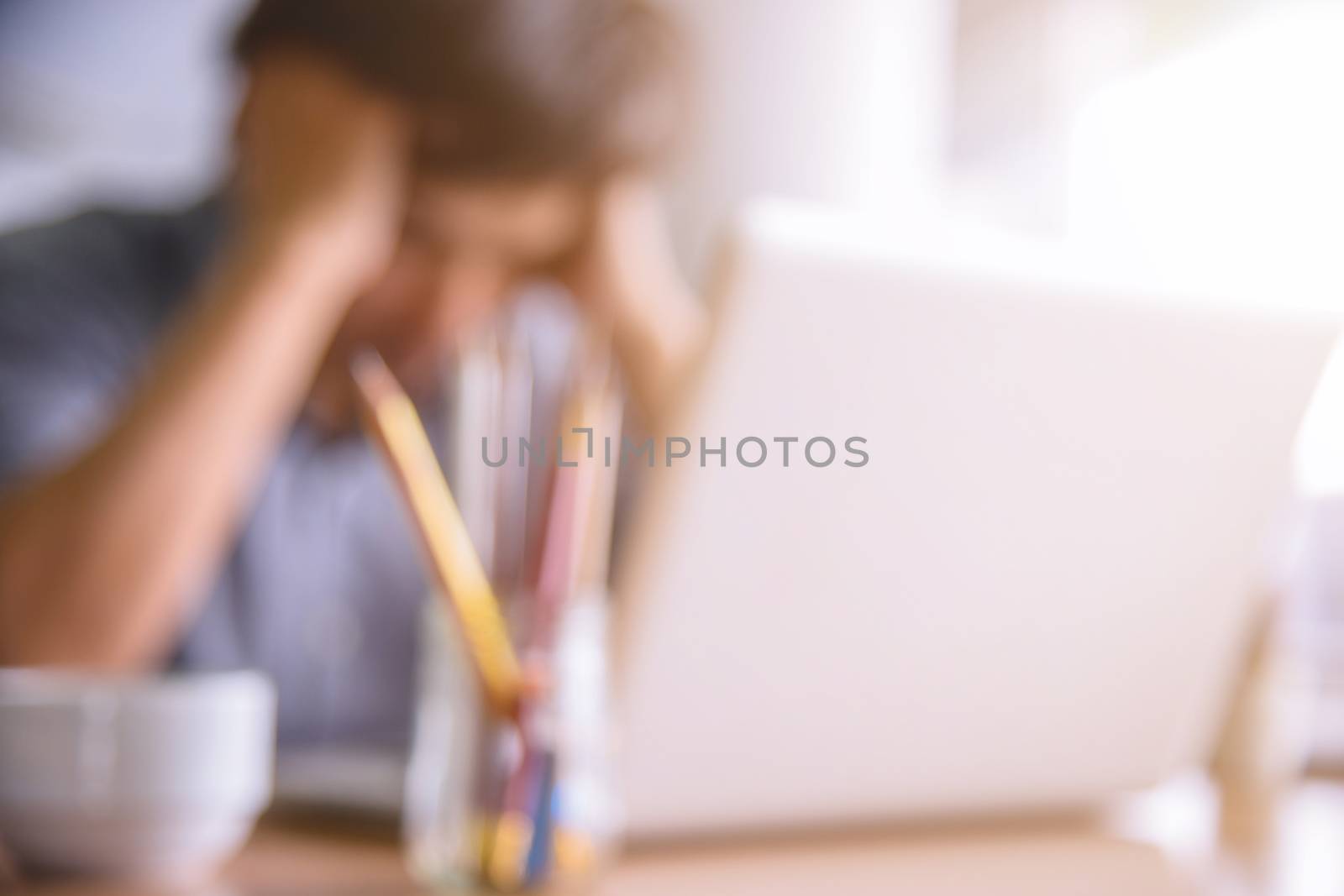 Blurred defocused a man strain on earnings at office desk by NuwatPhoto