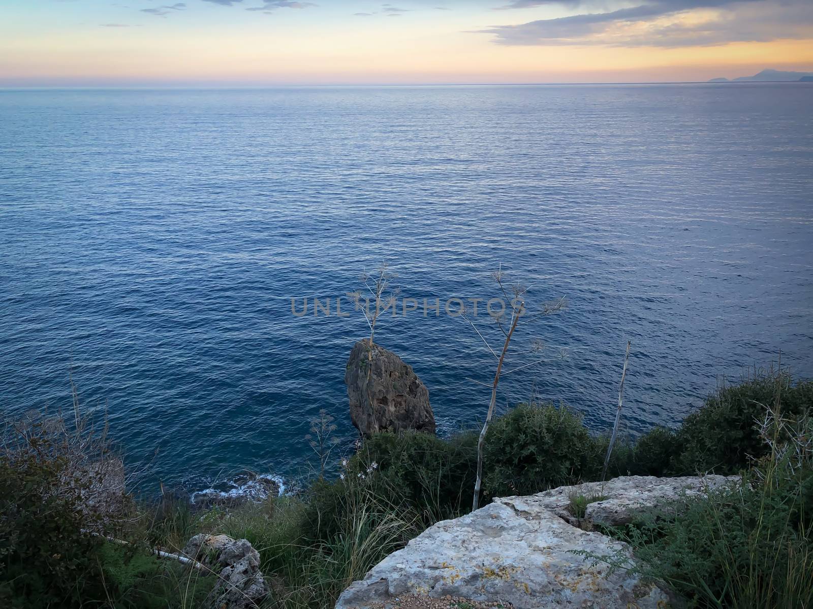 Landscape of blue Mediterranean sea rocks sunset and cloudy sky in Antalya