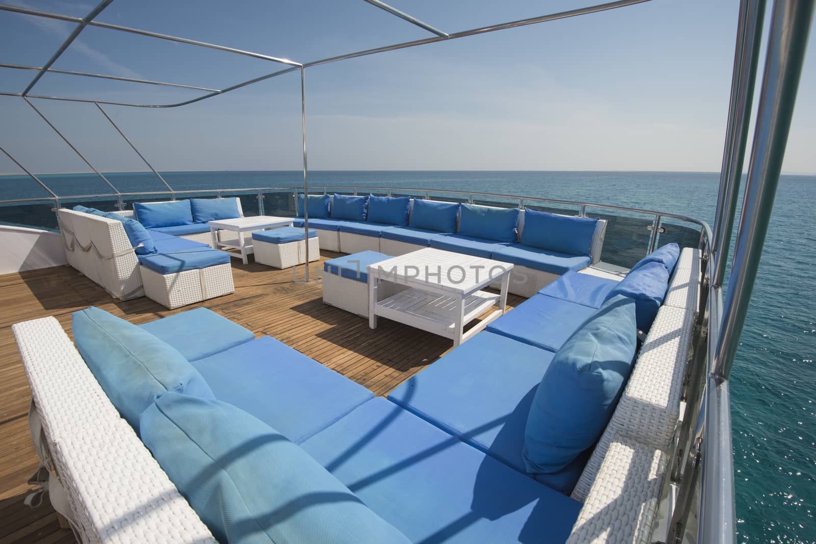 Rear teak deck of a large luxury motor yacht with chairs sofa table and tropical sea view background