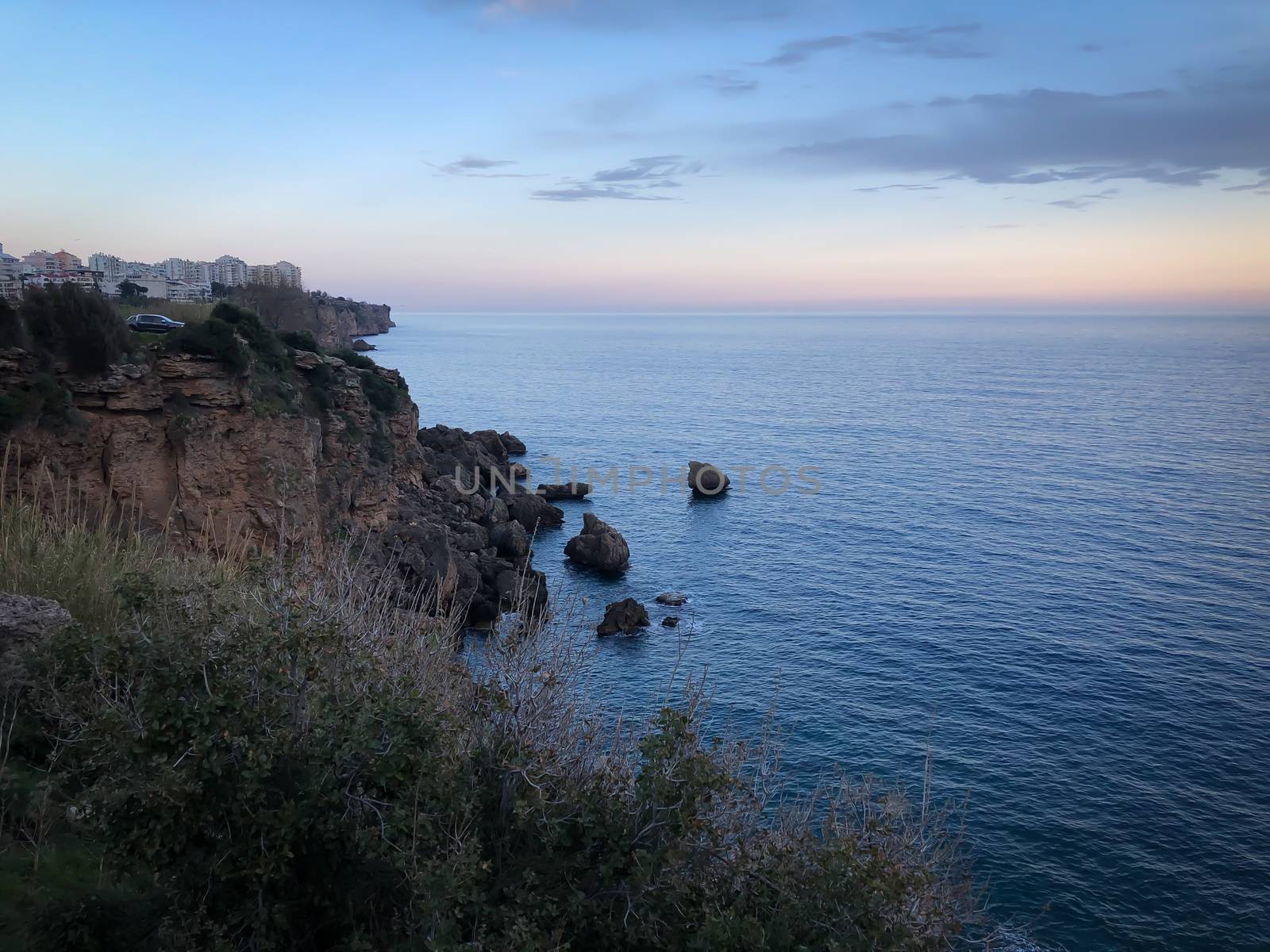 Landscape of blue Mediterranean sea rocks sunset and cloudy sky in Antalya