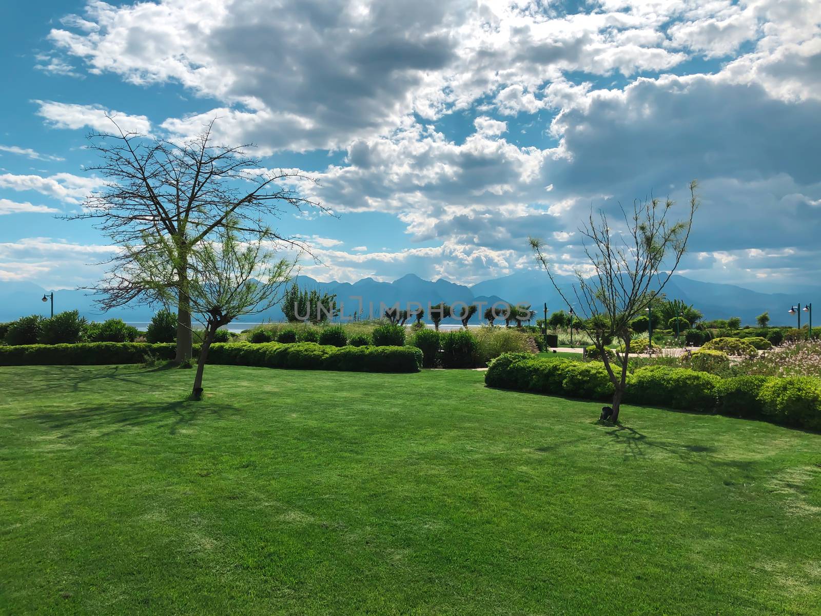 Beautiful green park in Antalya with mountains and Mediterranean sea on a background. Horizontal pure nature stock image