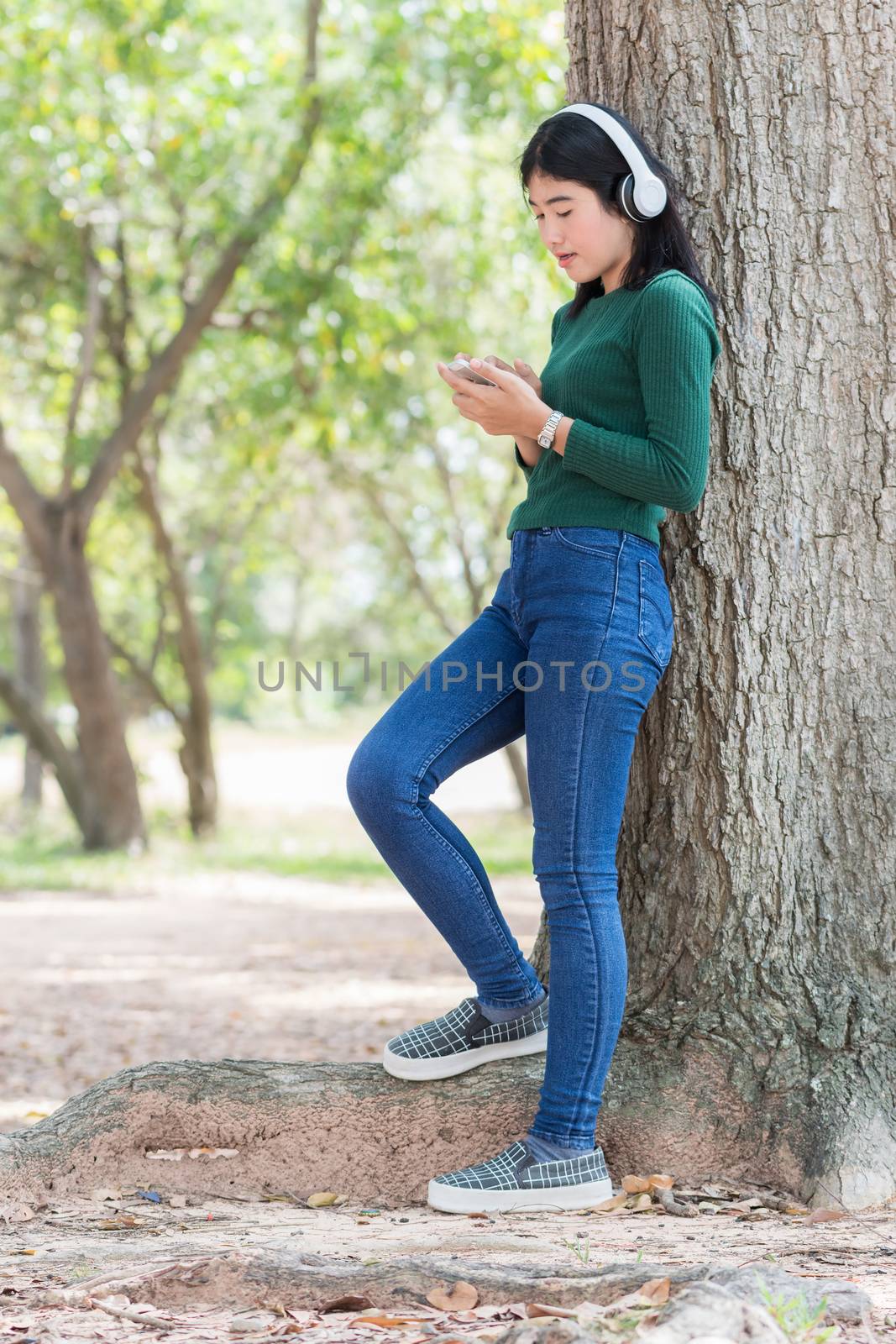 Young beautiful woman girl listening music headphones outdoor by Kumma