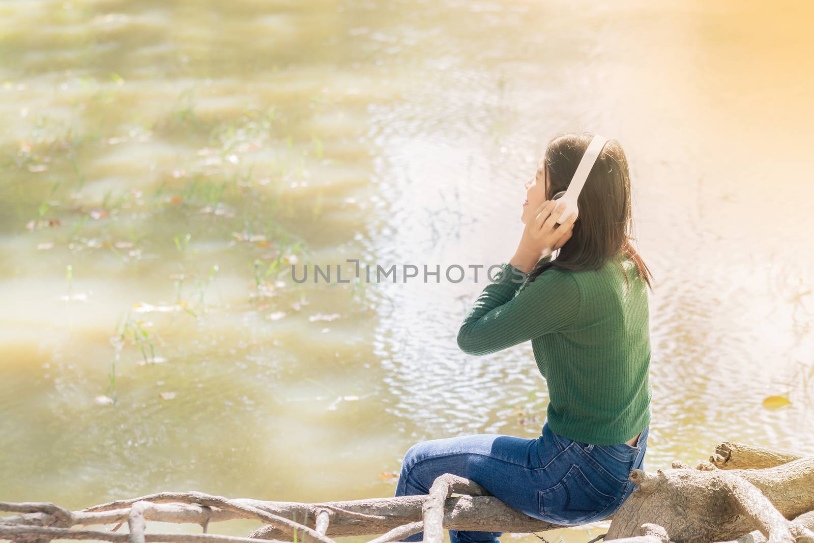 Young beautiful woman girl listening music headphones outdoor by Kumma
