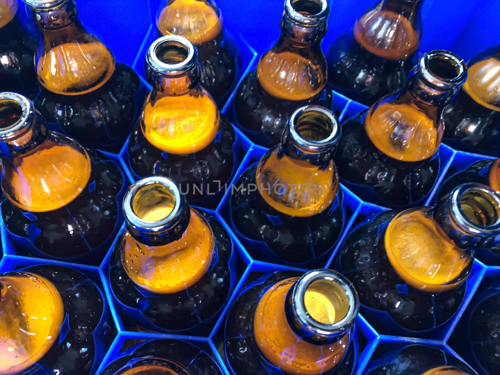 Blue plastic honeycombs shaped case  with full brown glass beer bottles. Horizontal stock image