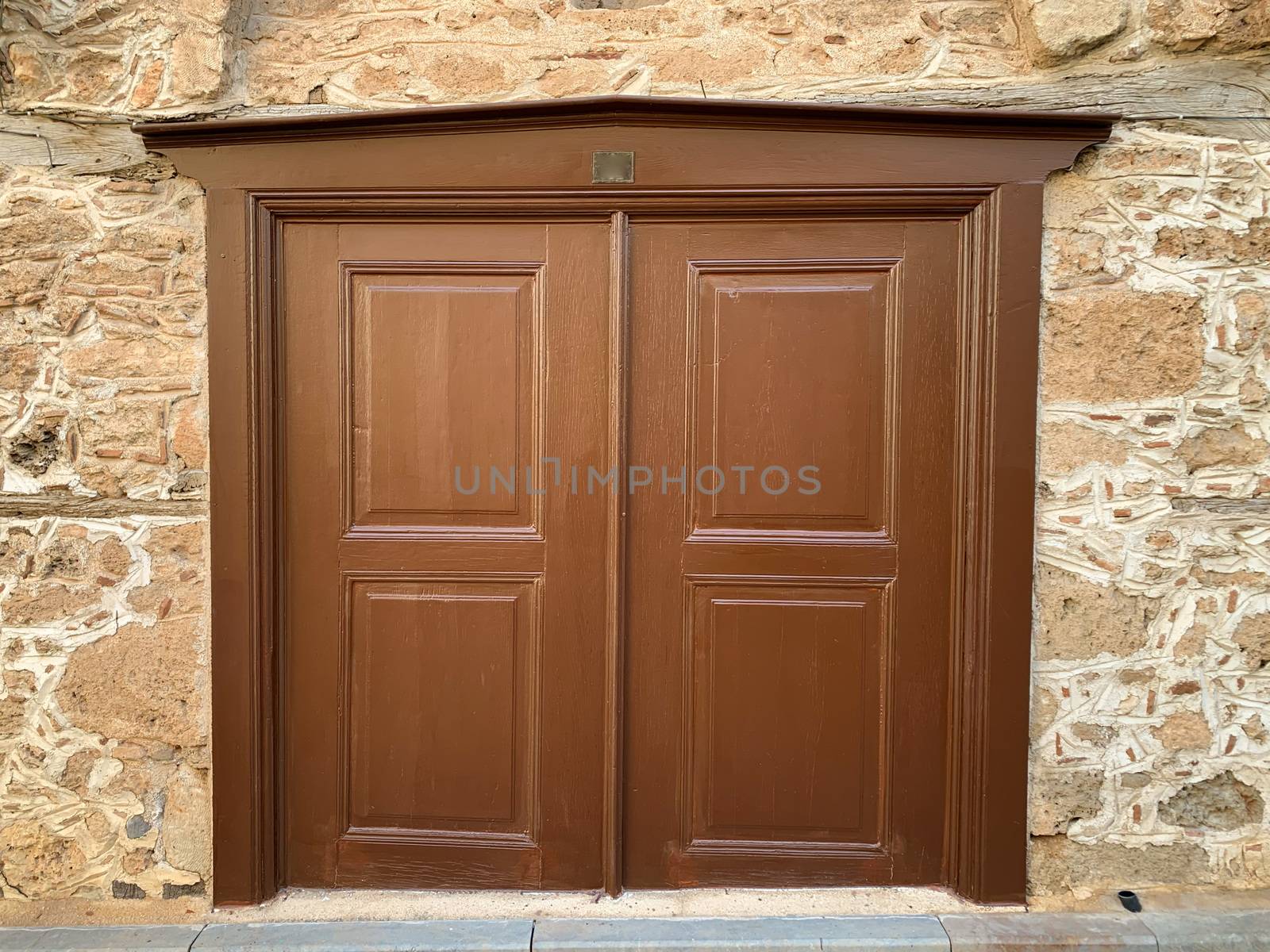 An old historical stone wall with a wooden door in Antalya Old town Kaleici, Turkey. Ottoman time architecture. Horizontal stock photo.