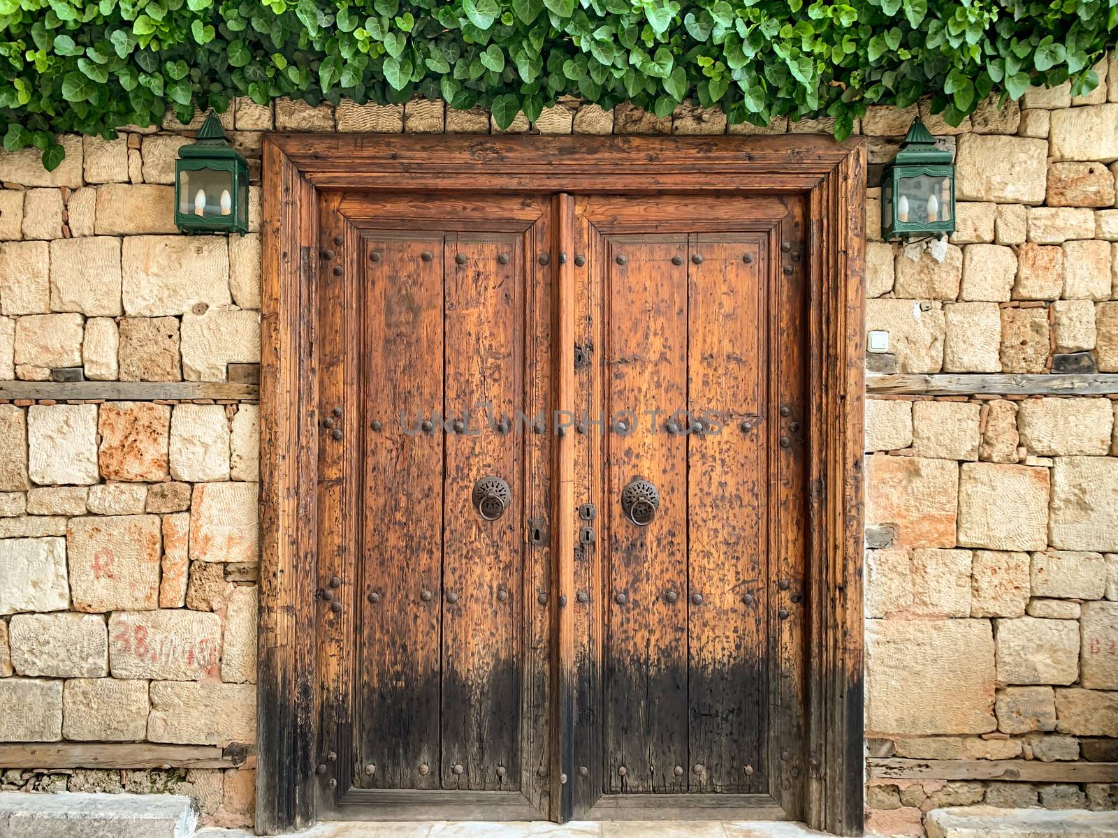 An old historical stone wall with a wooden door gate in Antalya Old town Kaleici, Turkey. Ottoman time architecture. Horizontal stock photo.
