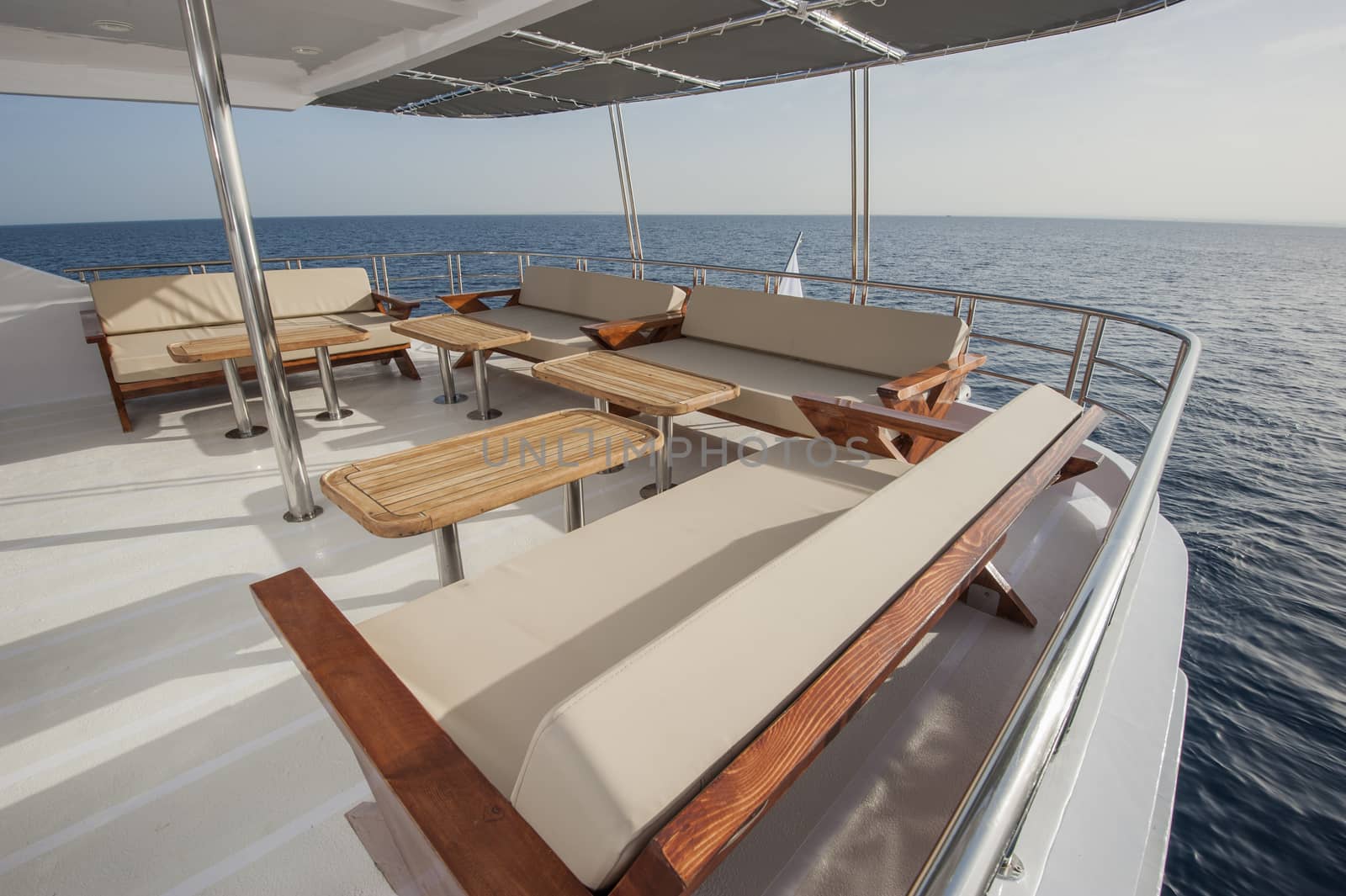 Table and chairs on deck of a luxury motor yacht by paulvinten