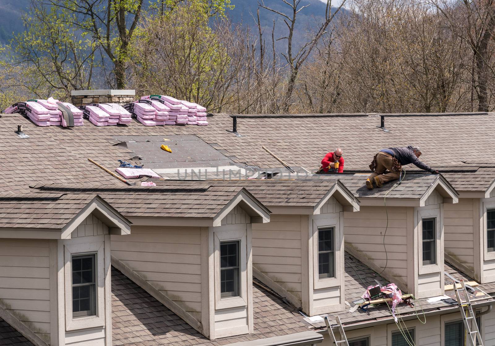 Morgantown, WV - 18 April 2020: Roofing contractors replacing the old shingles on a townhouse roof