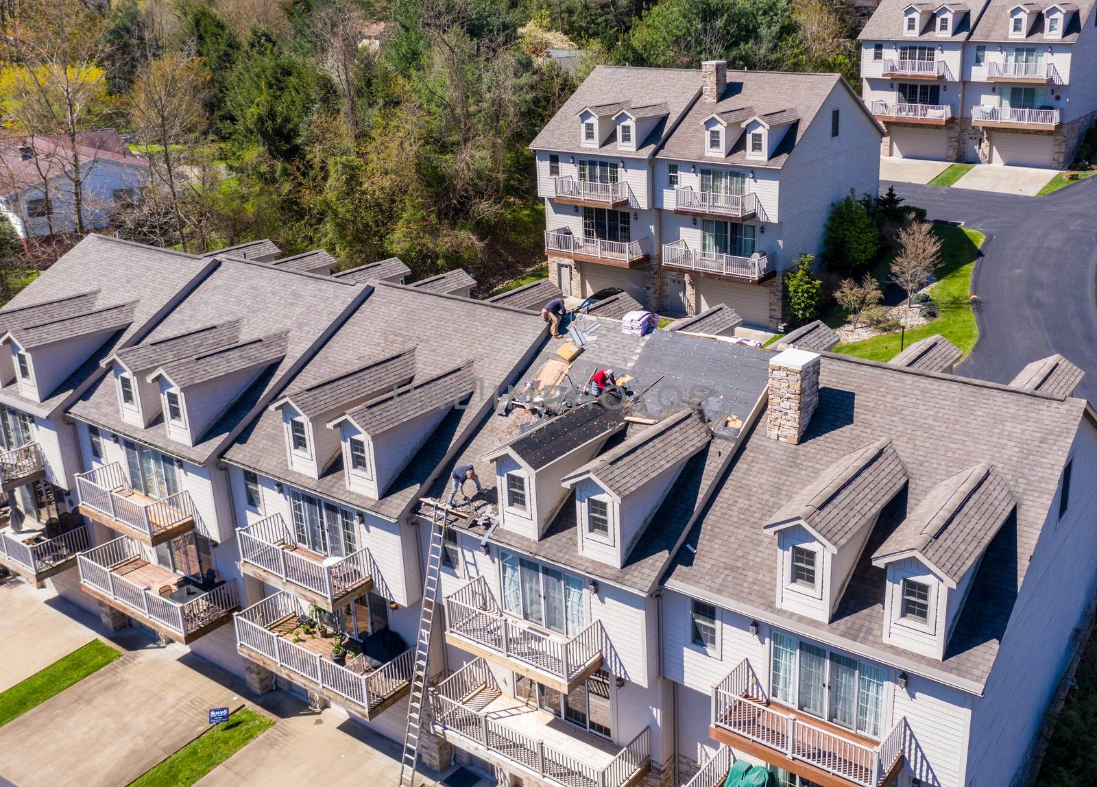 Morgantown, WV - 22 April 2020: Aerial view of roofing contractors replacing the old shingles on a townhouse roof