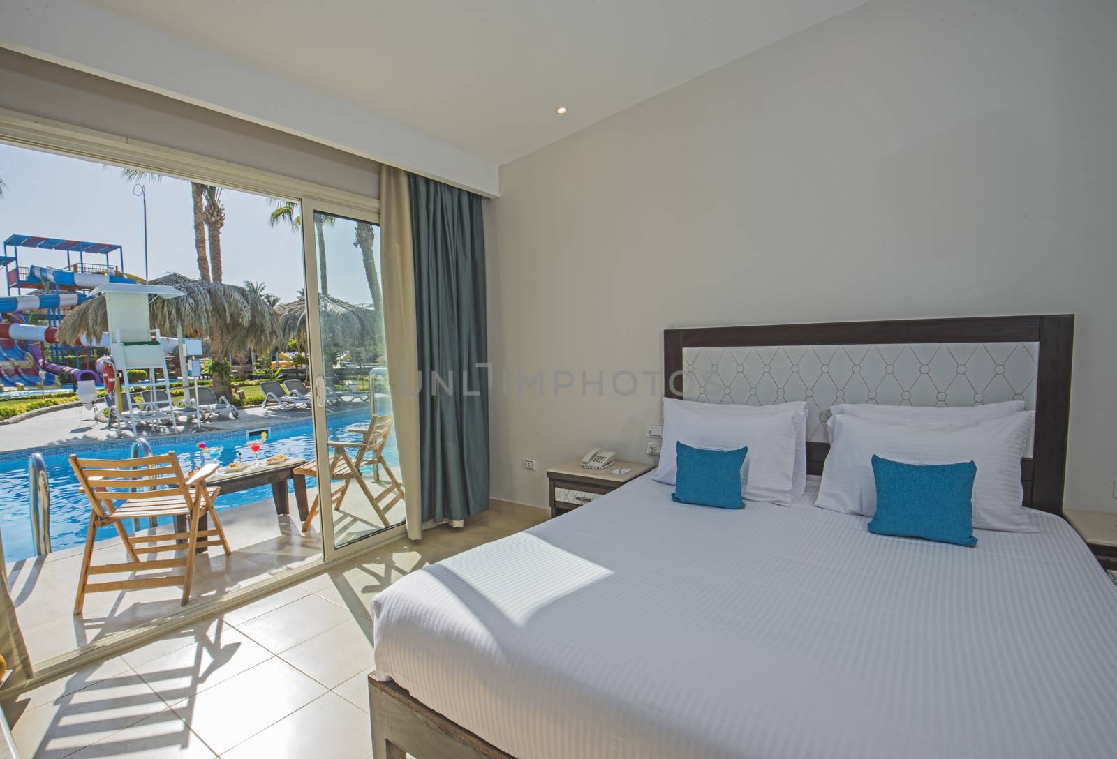 Double bed in suite of a luxury hotel room with terrace and pool view