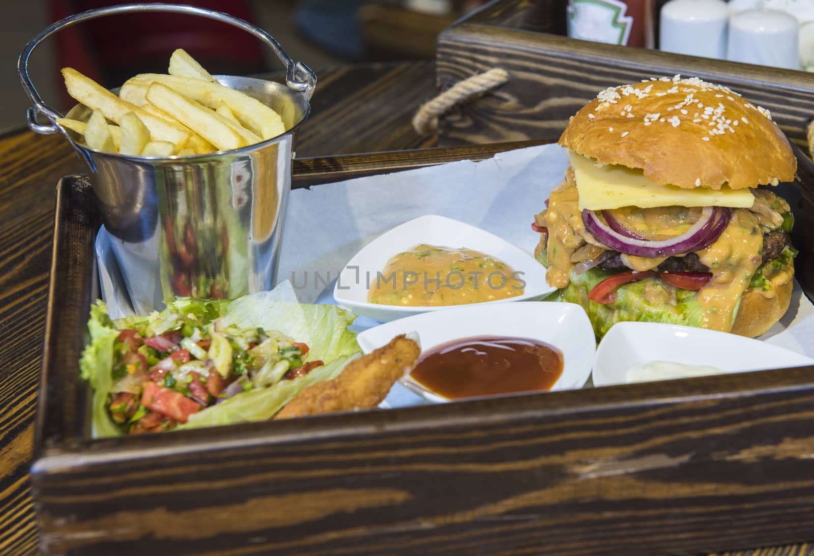 Luxury beef burger and salad meal on a tray with sauces in restaurant