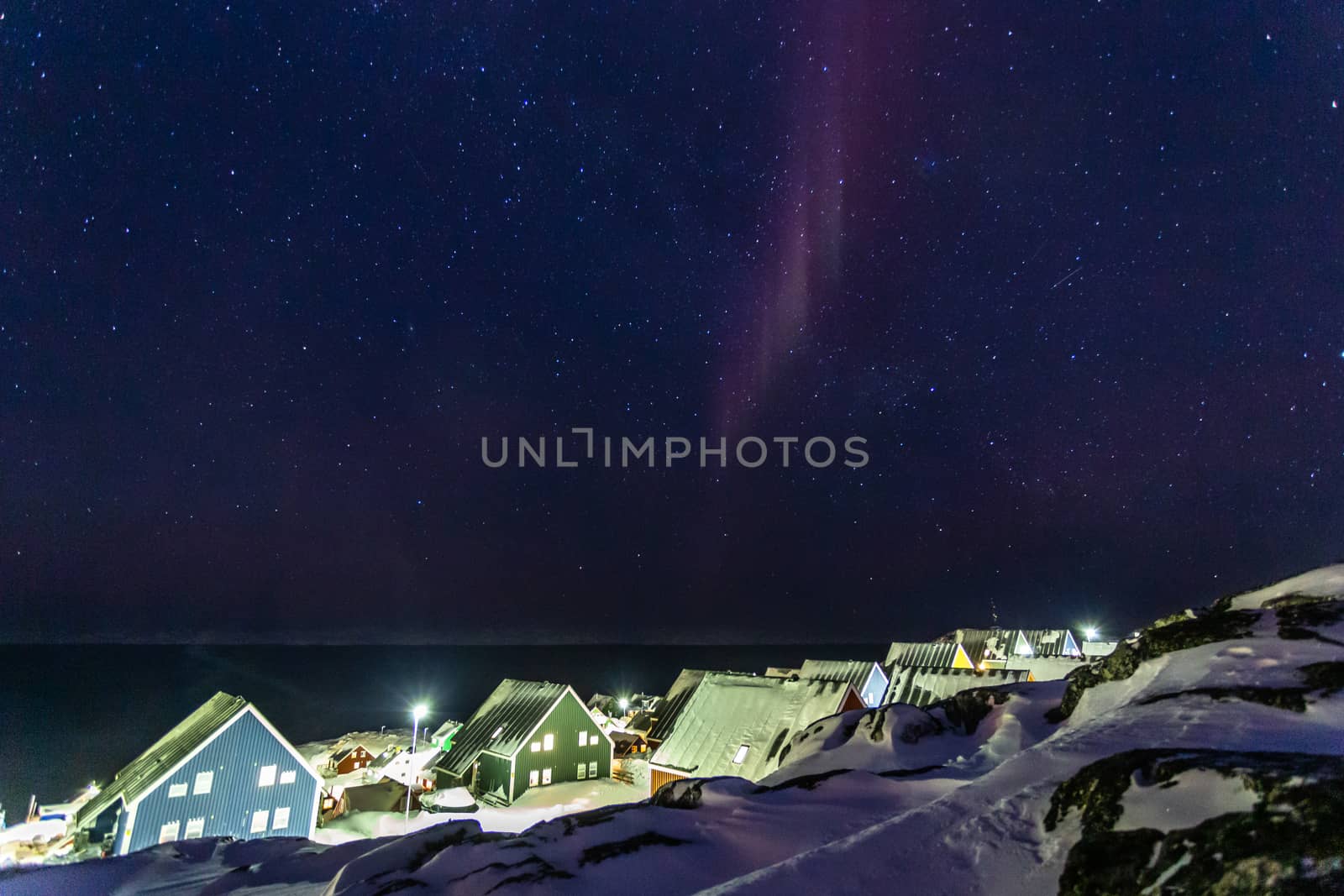 Arctic polar night over colorful inuit houses with small northern light in a suburb of arctic capital Nuuk, Greenland