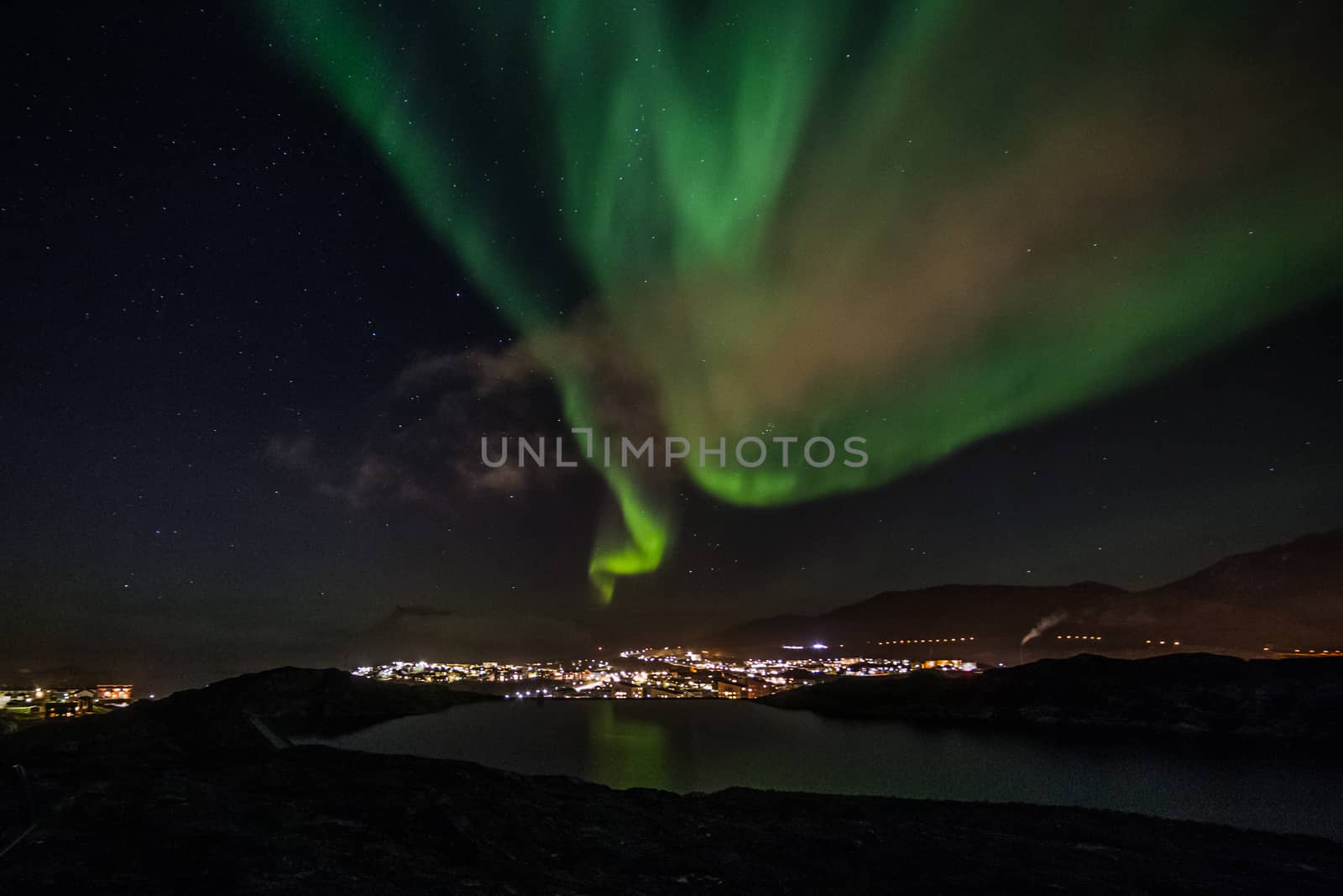 Massive green Aurora Borealis Northern lights shining over the lake and Nuuk city, Greenland