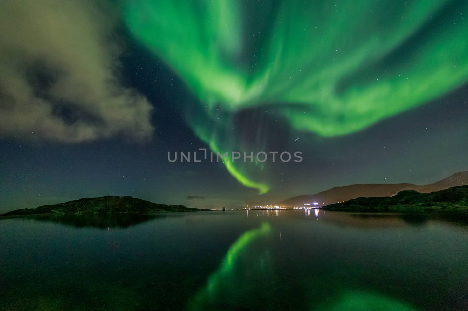 Green Northern lights reflecting in the lake with mountains and  by ambeon
