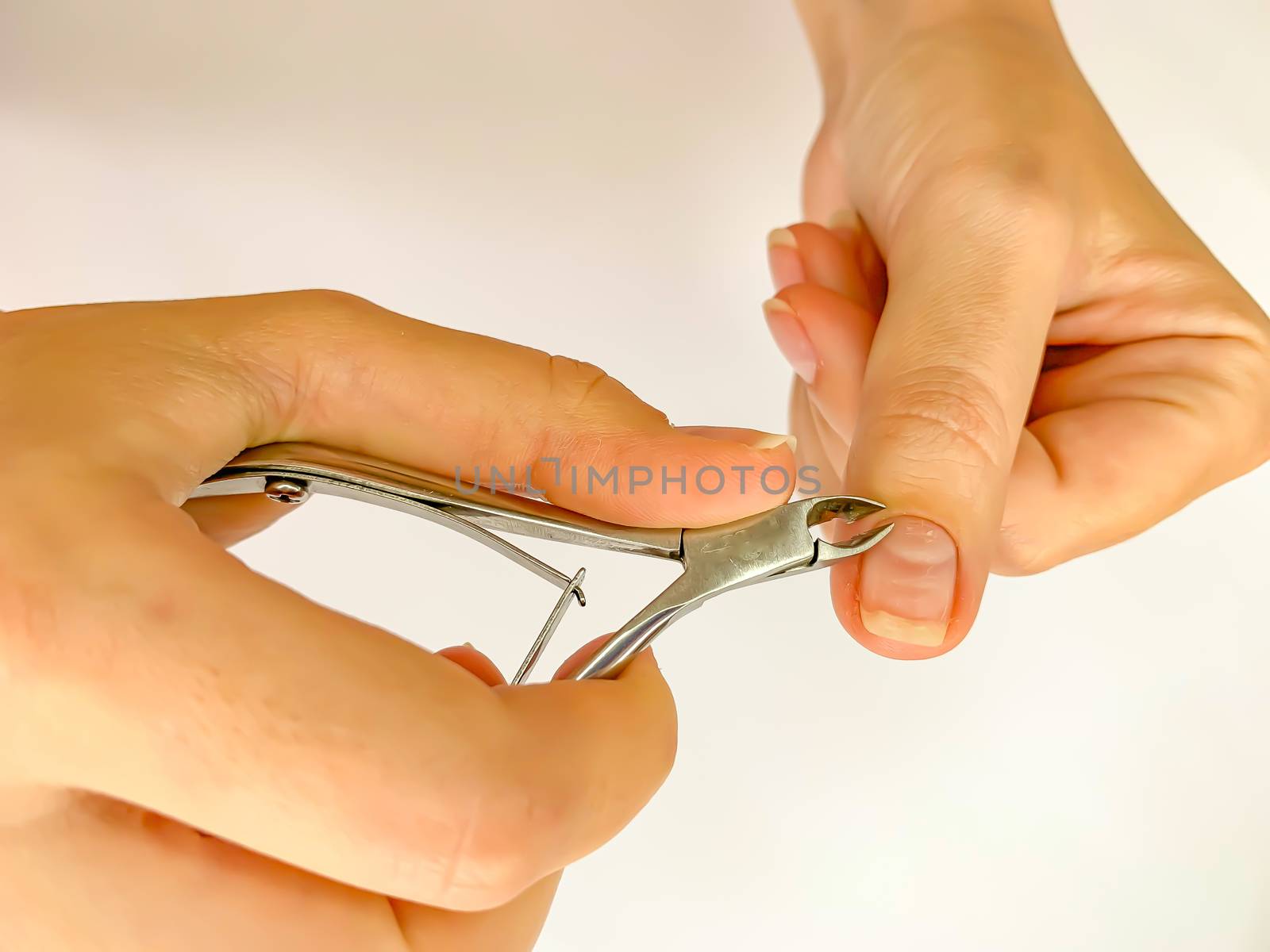 Close up of hands. Self manicure at home trimming cuticles on white background. Manicure and skin care. 