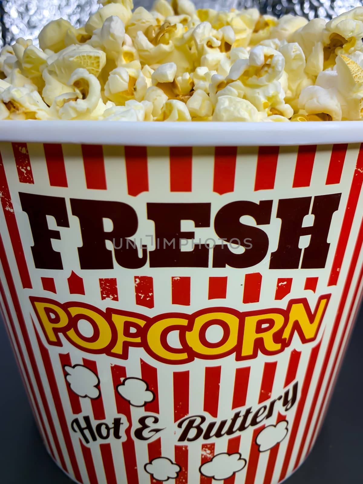 Close up delicious fresh buttery popcorn in a stripped red and white bowl on gray background