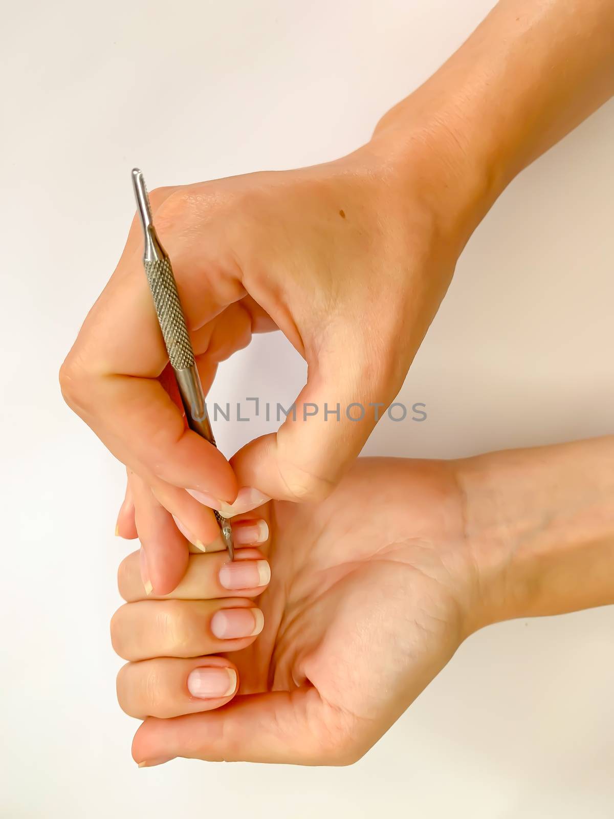 Female woman doing manicure at home on a white background. Self manicure close up