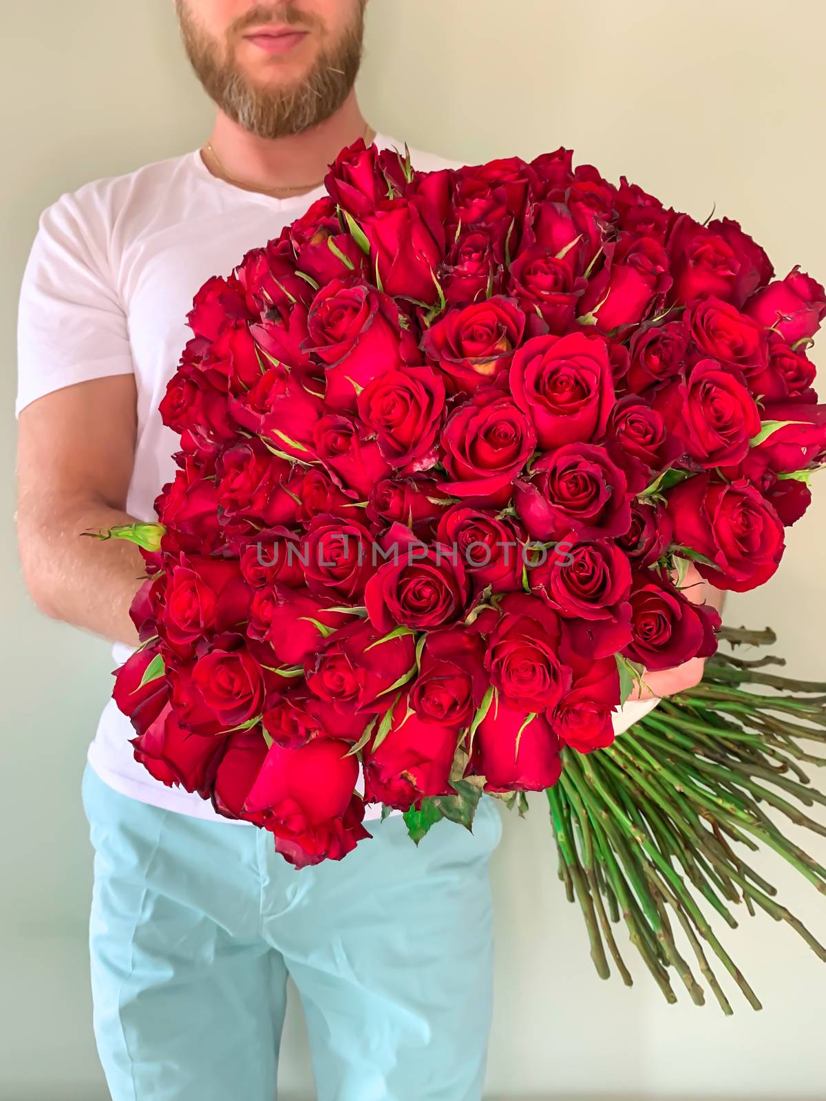 Bearded man in white t shirt holding in hands rich gift bouquet  by AlonaGryadovaya