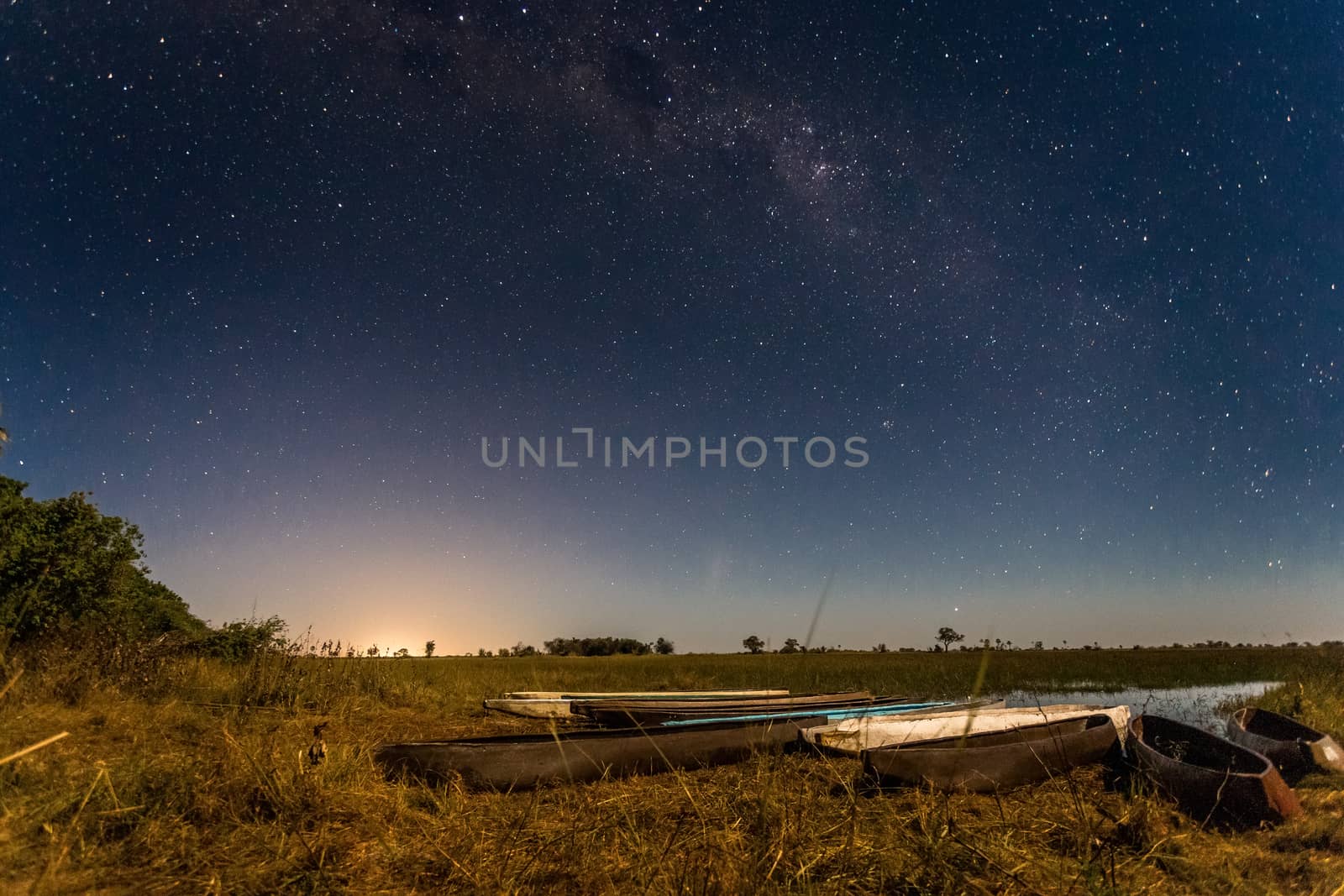 Botswanian local mokoro boats under the starlight sky, on the shore of delta Okavango river, Botswana