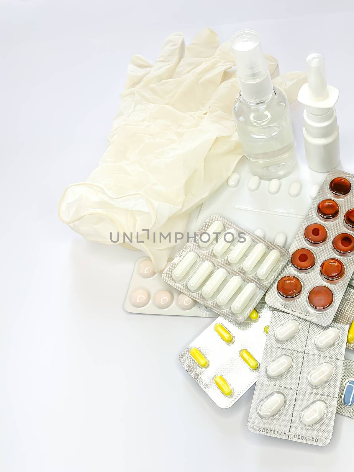 Different medicines: tablets, pills in blister pack, medications drugs, medical gloves, mask, syringe, thermometer, spray, sanitizer on a white background. Vertical photo with space for text