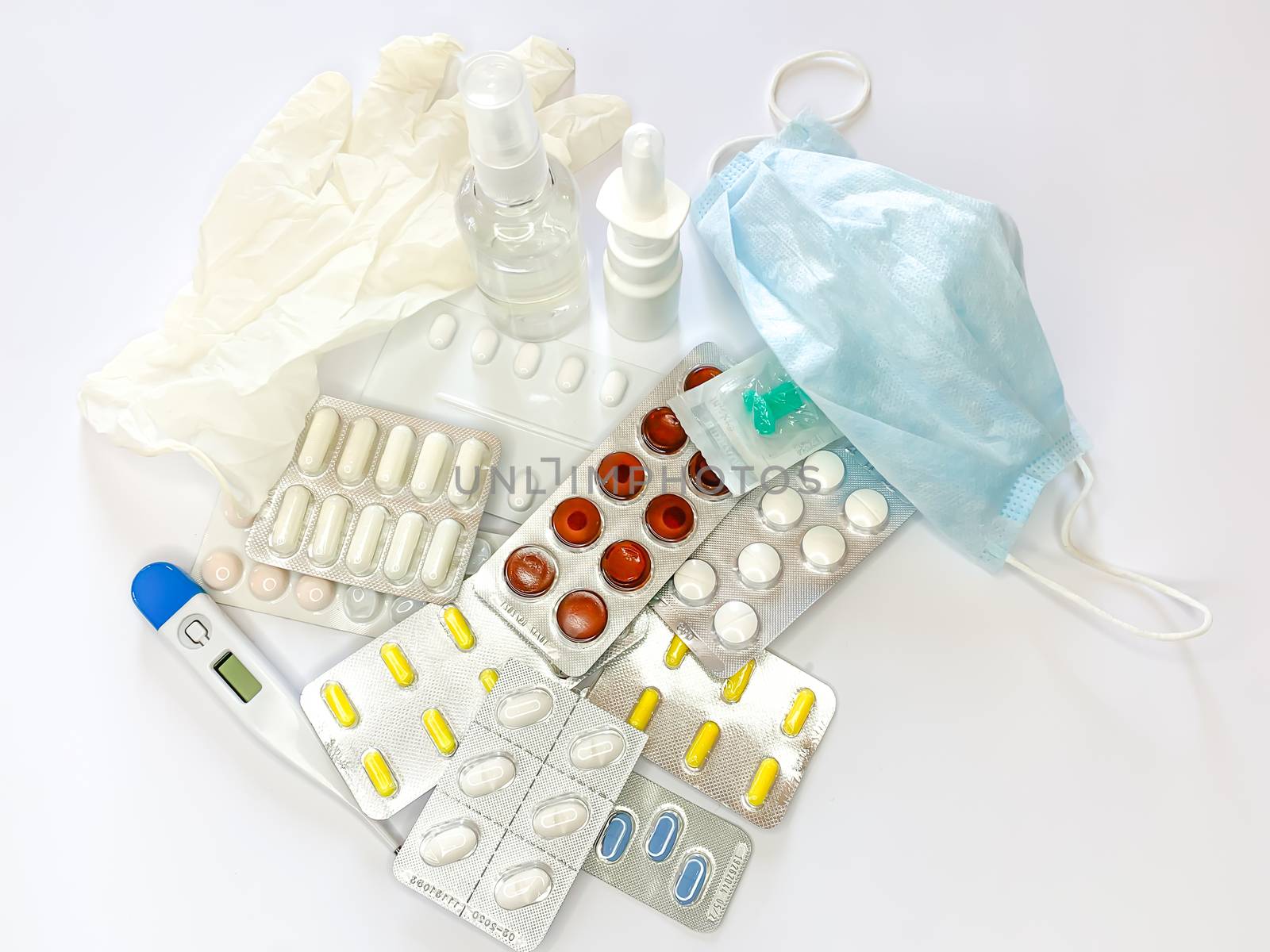 Many different medicines: tablets, pills in blister pack, medications drugs, medical gloves, mask, syringe, thermometer, spray, sanitizer on a white background. Horizontal photo