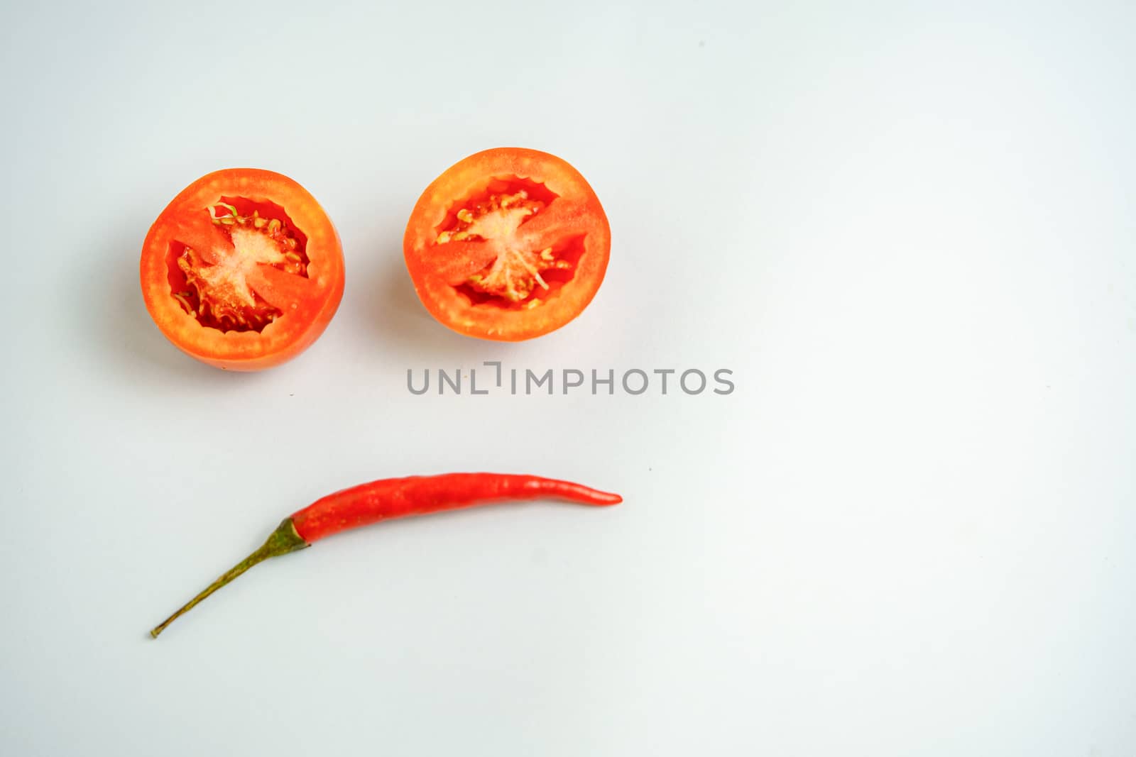 Red tomatoes and red peppers are sad in the white background