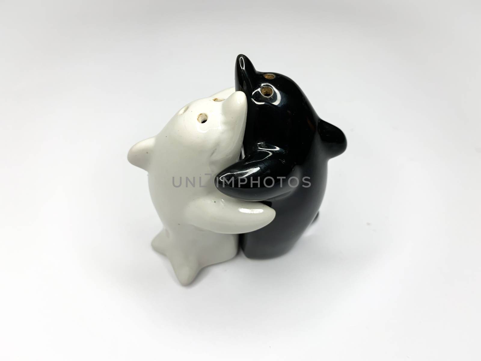 Black and white yin yang dolphin shaped salt and pepper shakers hugging each other on white background