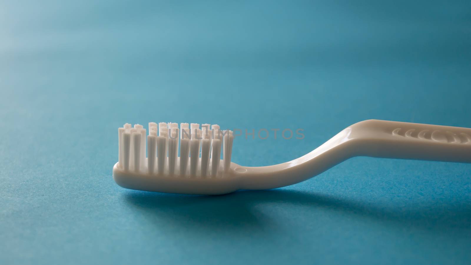 Close up plastic white tooth brush on blue background dental hyg by AlonaGryadovaya