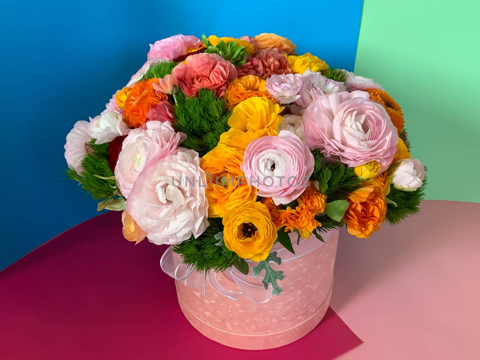 Bright colorful pink yellow orange persian asian buttercup ranunculus asiaticus bouquet fresh flowers in round box