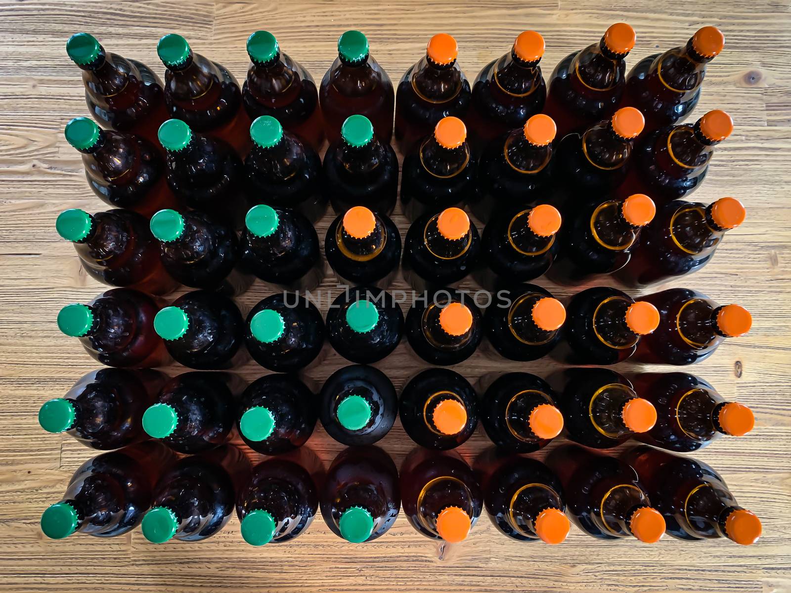 A lot of home brewery self made beer. Many brown glass craft beer bottles with green and orange corks, flat top view on a wooden texture horizontal image.