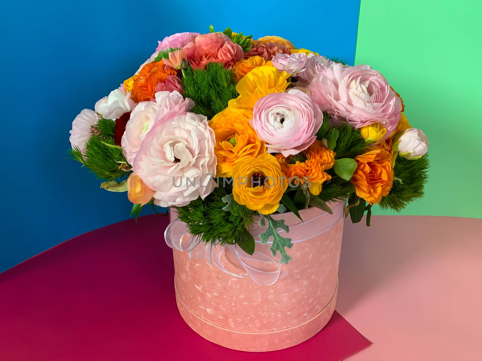 Bright colorful pink yellow orange persian asian buttercup ranunculus asiaticus bouquet fresh flowers in round box