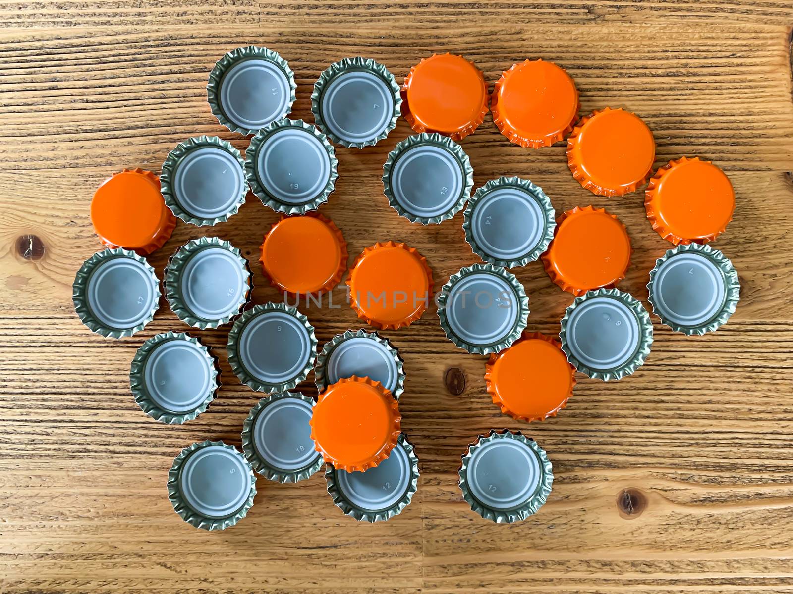 Many orange beer lids, bottle corks tops on a wooden texture top view horizontal image 