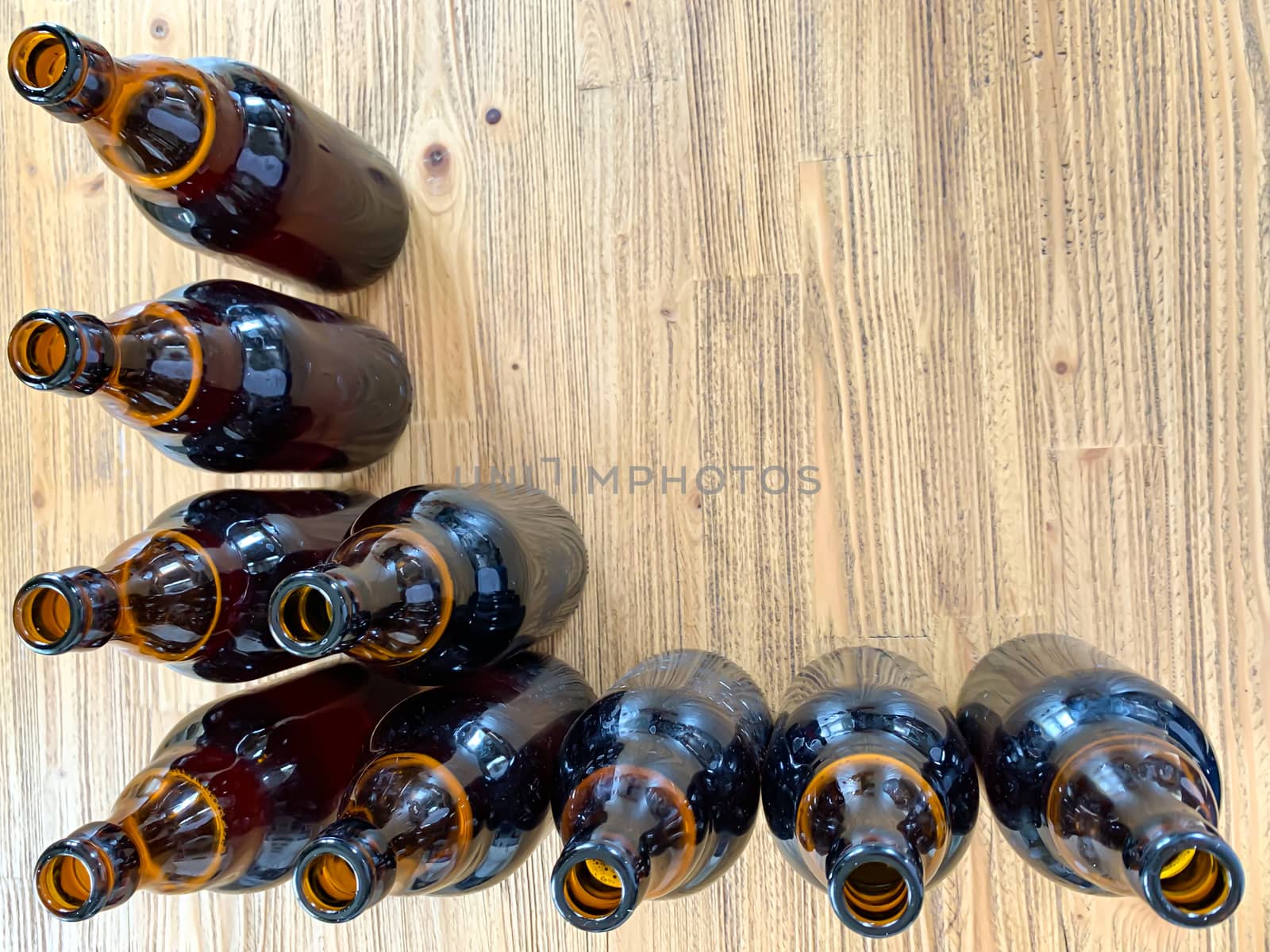 Brown glass craft beer bottle frame top view on a wooden background with empty space for text, vertical image