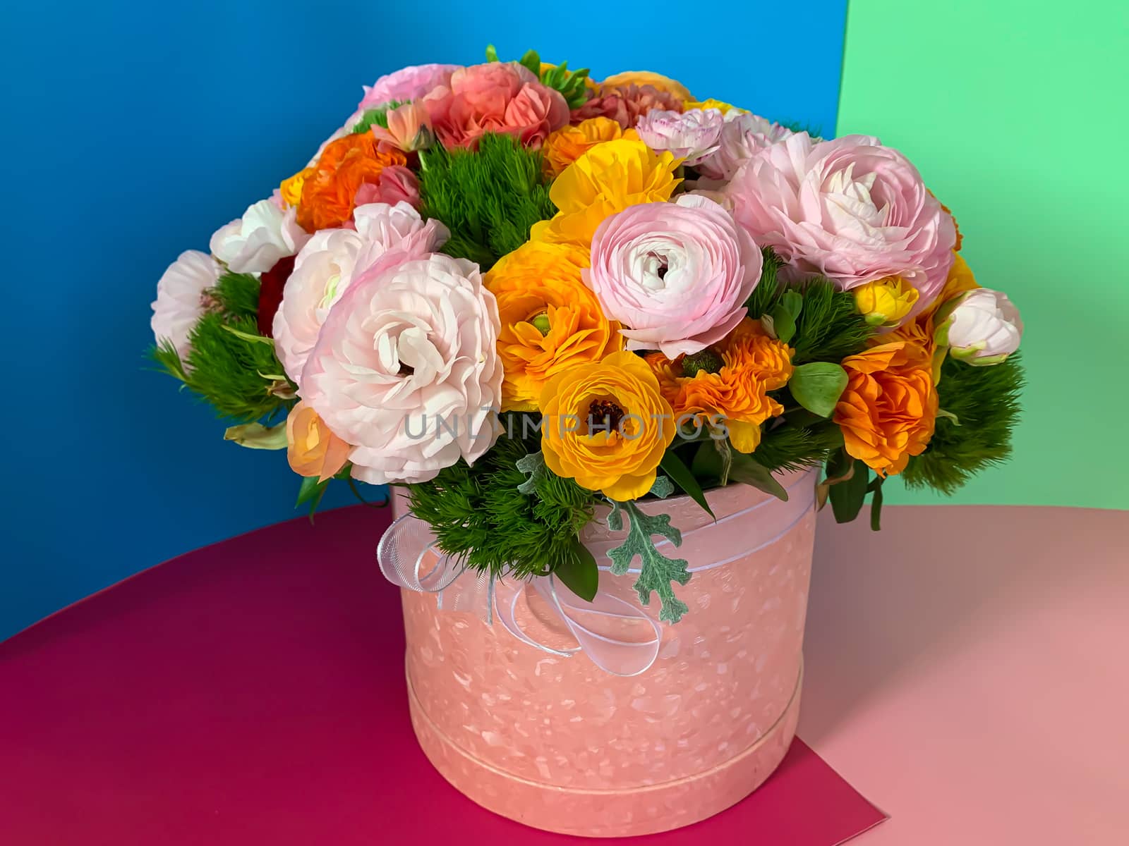 Bright colorful pink yellow orange persian asian buttercup ranunculus asiaticus bouquet fresh flowers in round box