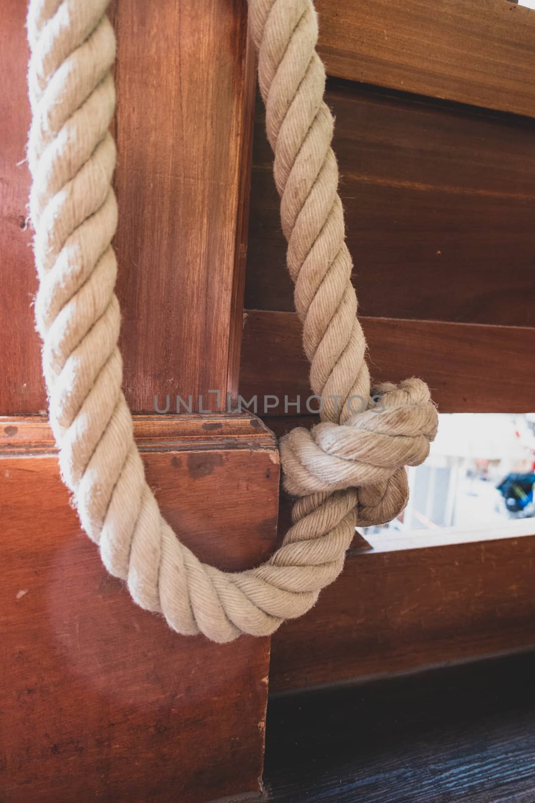 A rope made of natural fibre with a knot in the middle, which acts as a barrier rope open on a wooden mast.