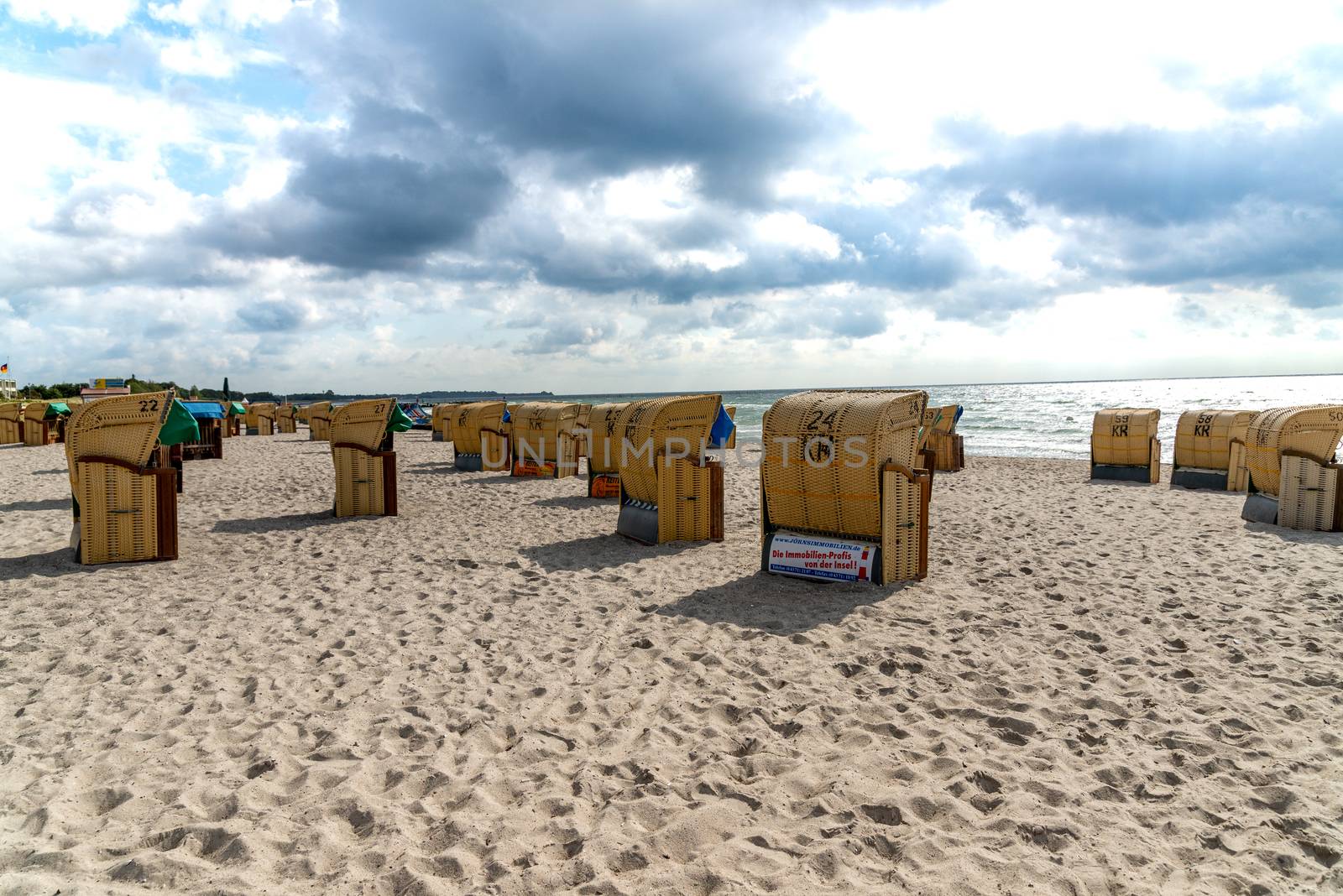 Fehmarn, Schleswig-Holstein/Germany - 05.09.2019: Beach on Fehmarn in Germany with many beach chairs on the beach and the Baltic Sea in the background with light-dark cloudy sky.