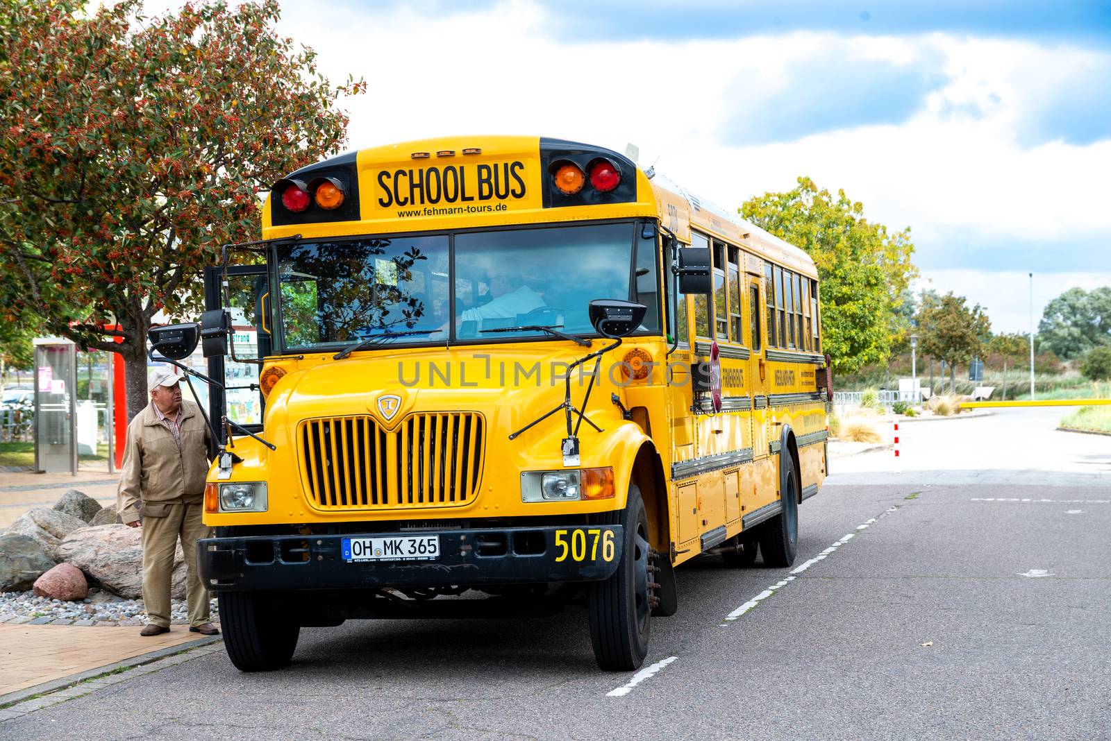 Fehmarn, Schleswig-Holstein/Germany - 05.09.2019: A yellow American school bus from excursion bus on the island of Fehmarn in Germany. At the side is the bus driver.
