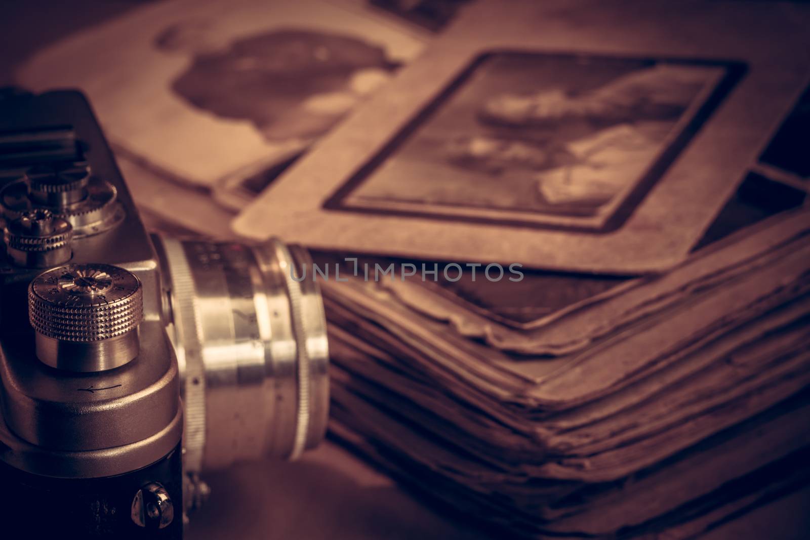 Photo of an old shabby family photo album. Old camera model on a background of an album with photos. Toned photo. Photo album with photos from the last century.