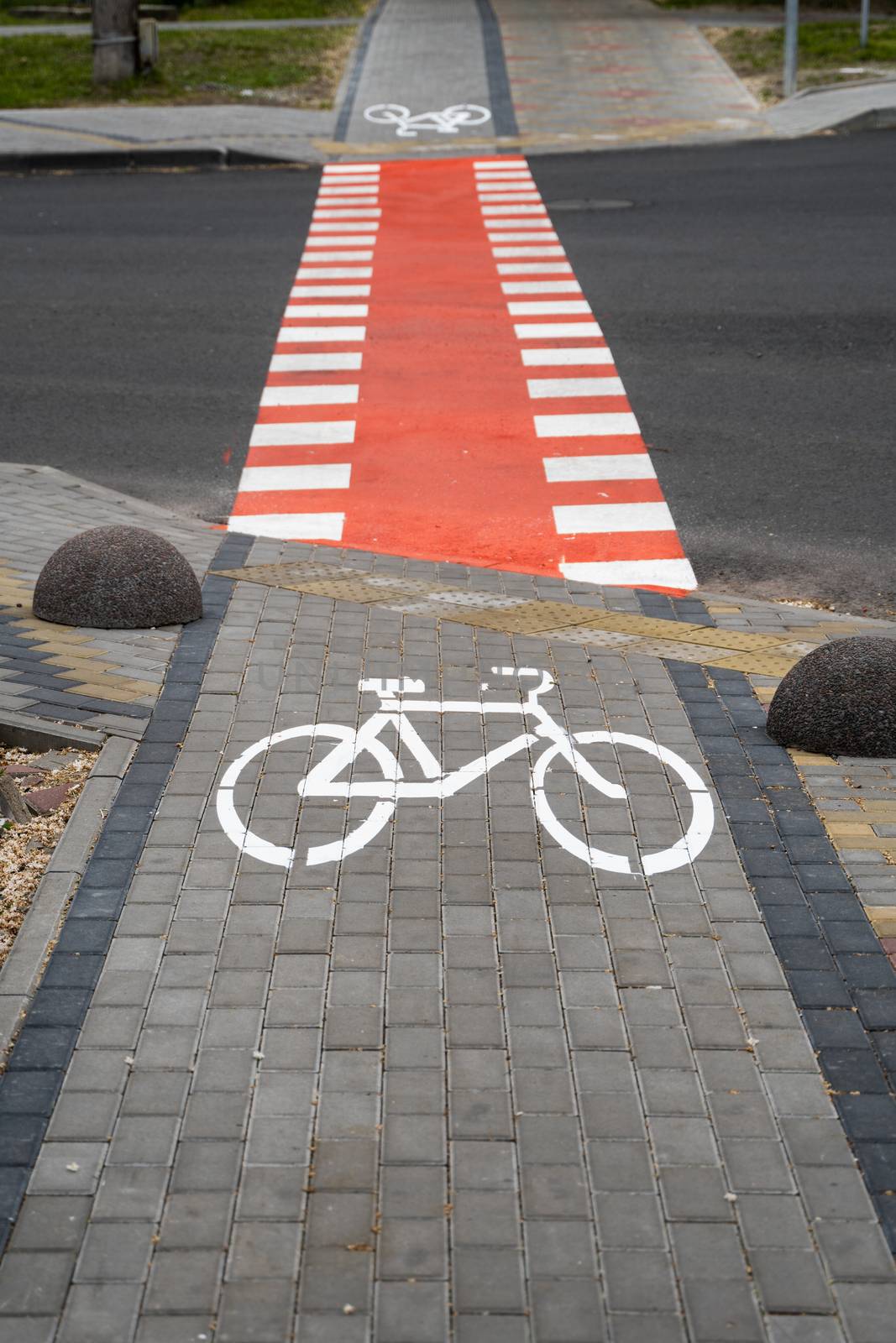 Cycling path with a symbol of bike on a ground through avtomobile road. Bike path in a modern city