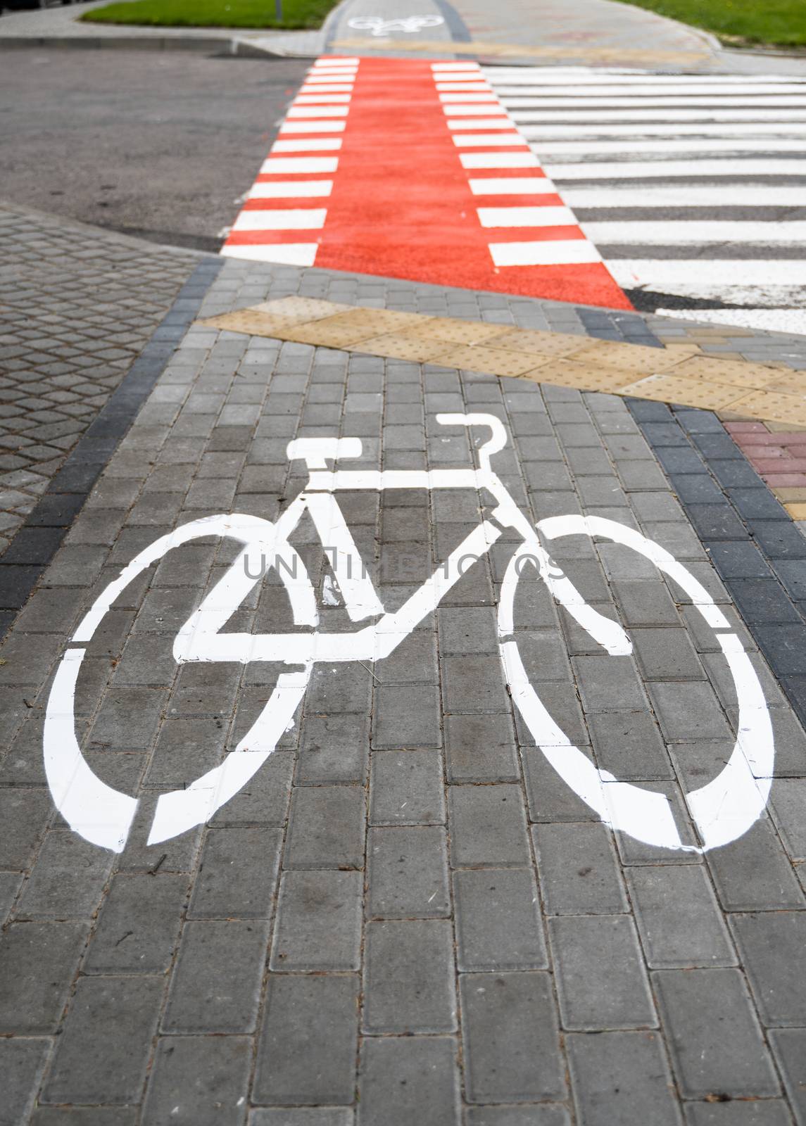 Cycling path with a symbol of bike on a ground through avtomobile road. Bike path in a modern city