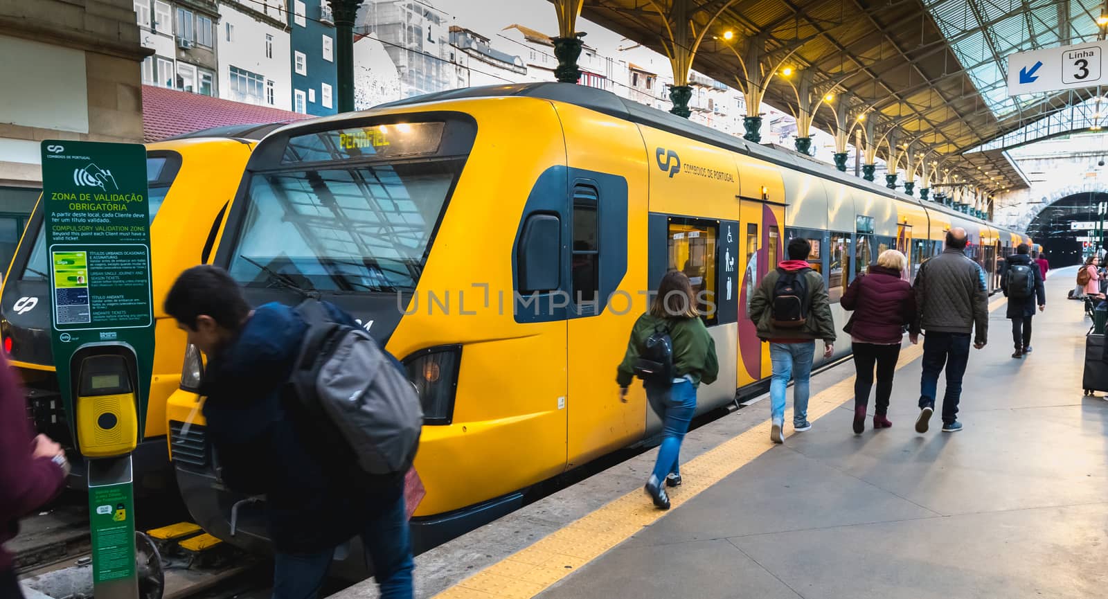 Porto, Portugal - November 30, 2018: Interior of Porto Sao Bento train station where people walk on the dock near the train stationary on a winter day