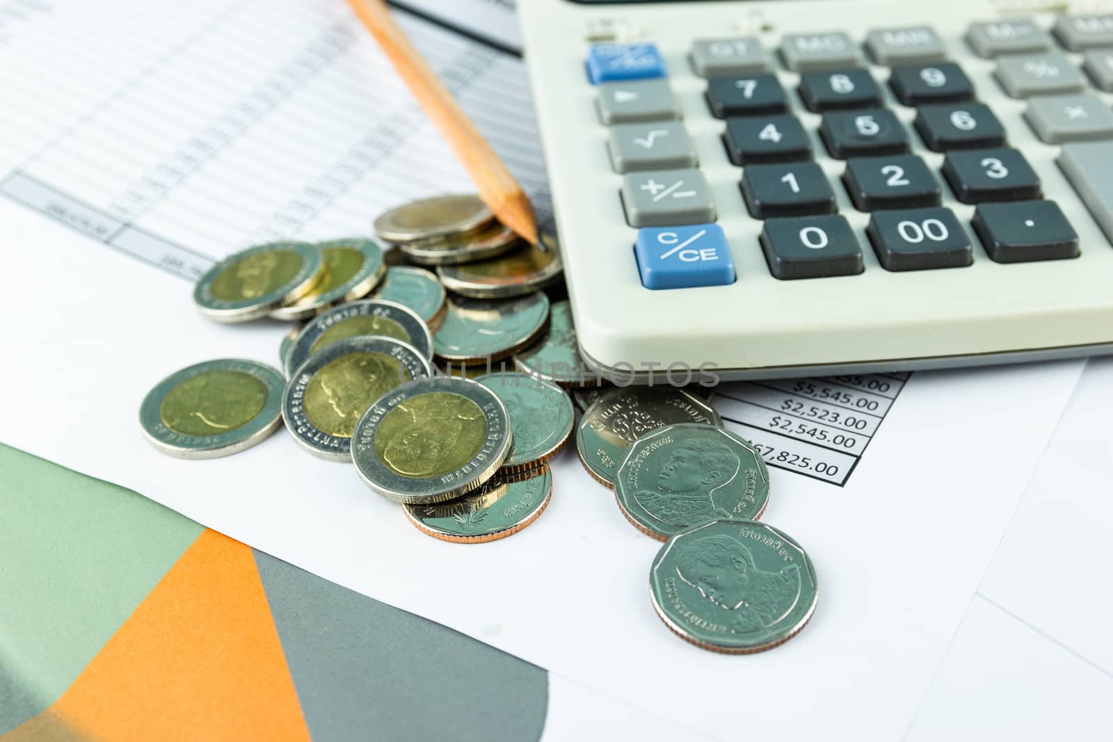 the stack of coin with business paper graphs and pencil with charts report, calculator, selective focus stack of coin, concept of calculating expenses, incomes and expenses.