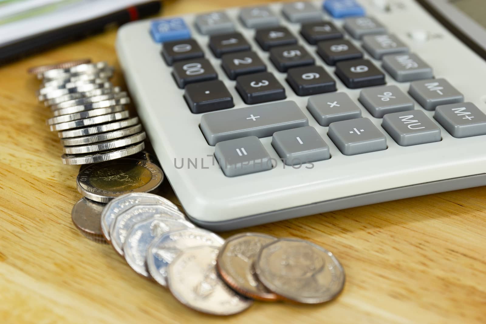 the stack of coin with calculator on wood table at office, concept of calculating expenses, incomes and expenses.