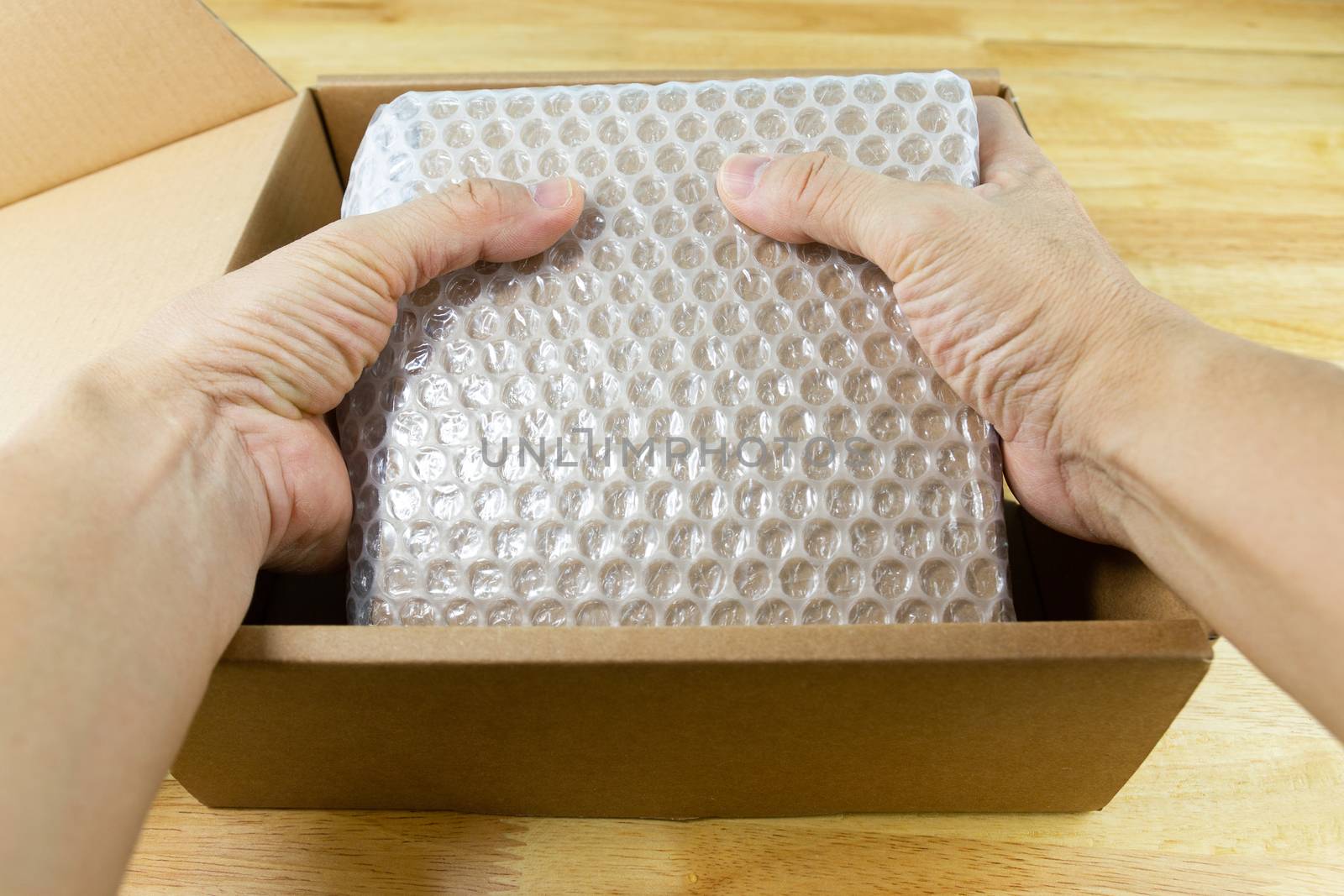 hand of man hold Bubbles covering the box by bubble wrap for protection product cracked  or insurance During transit - 