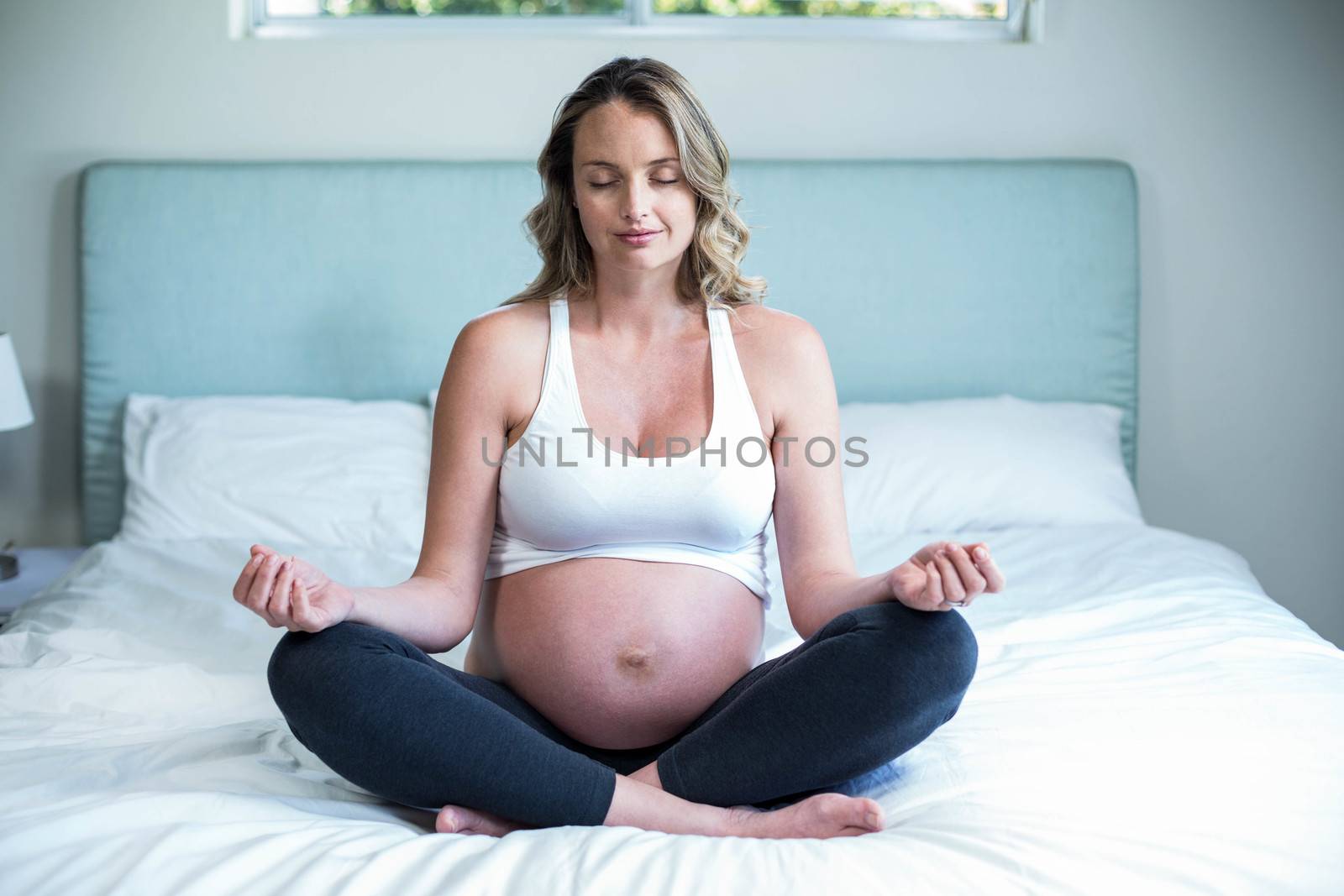 Pregnant woman doing yoga on her bed