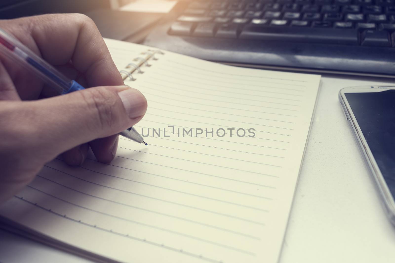 male hand writing in notebook with pen,
left hand
